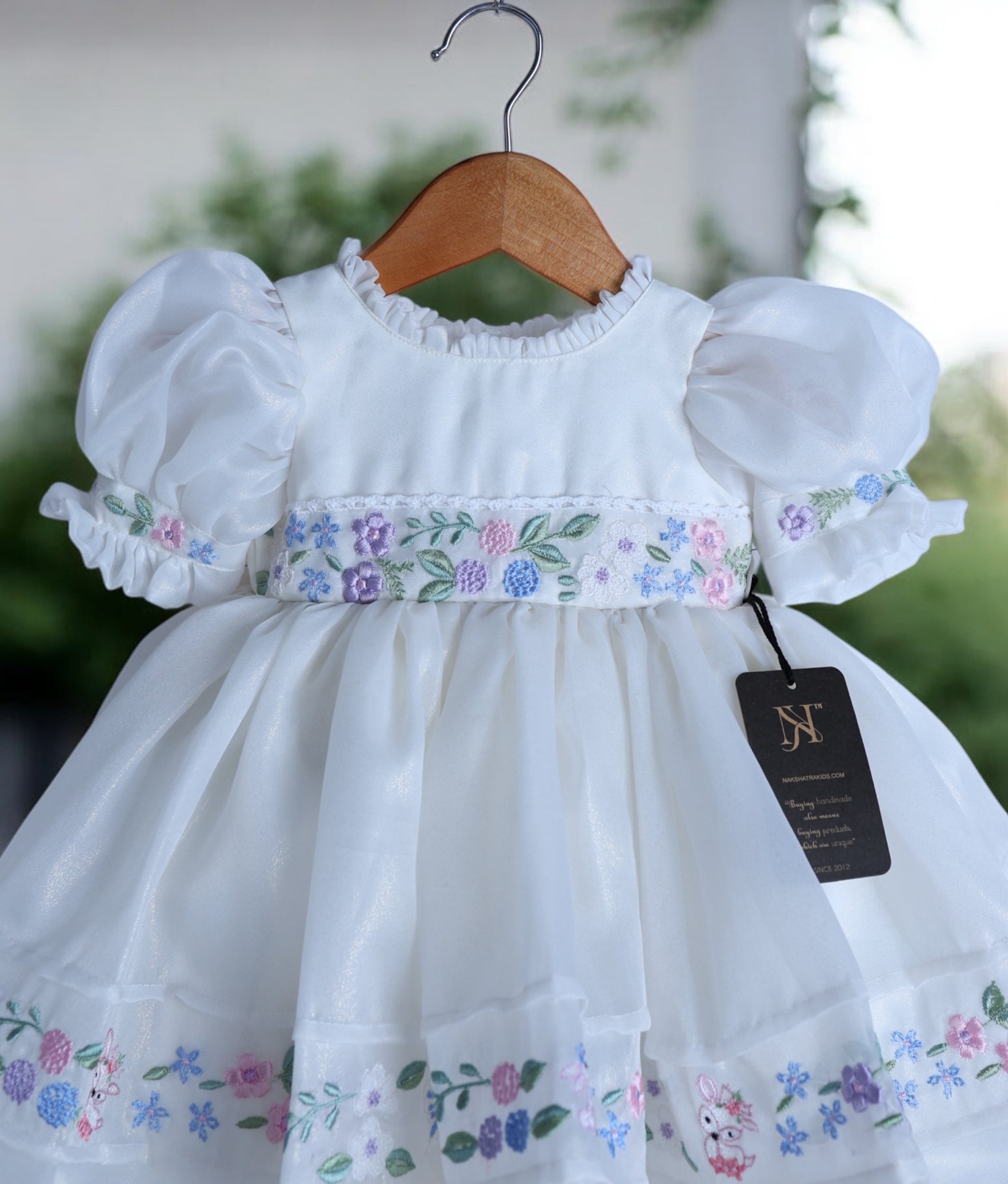 Close-up of whimsical machine embroidery with flowers and bunny figures on shimmer organza fabric