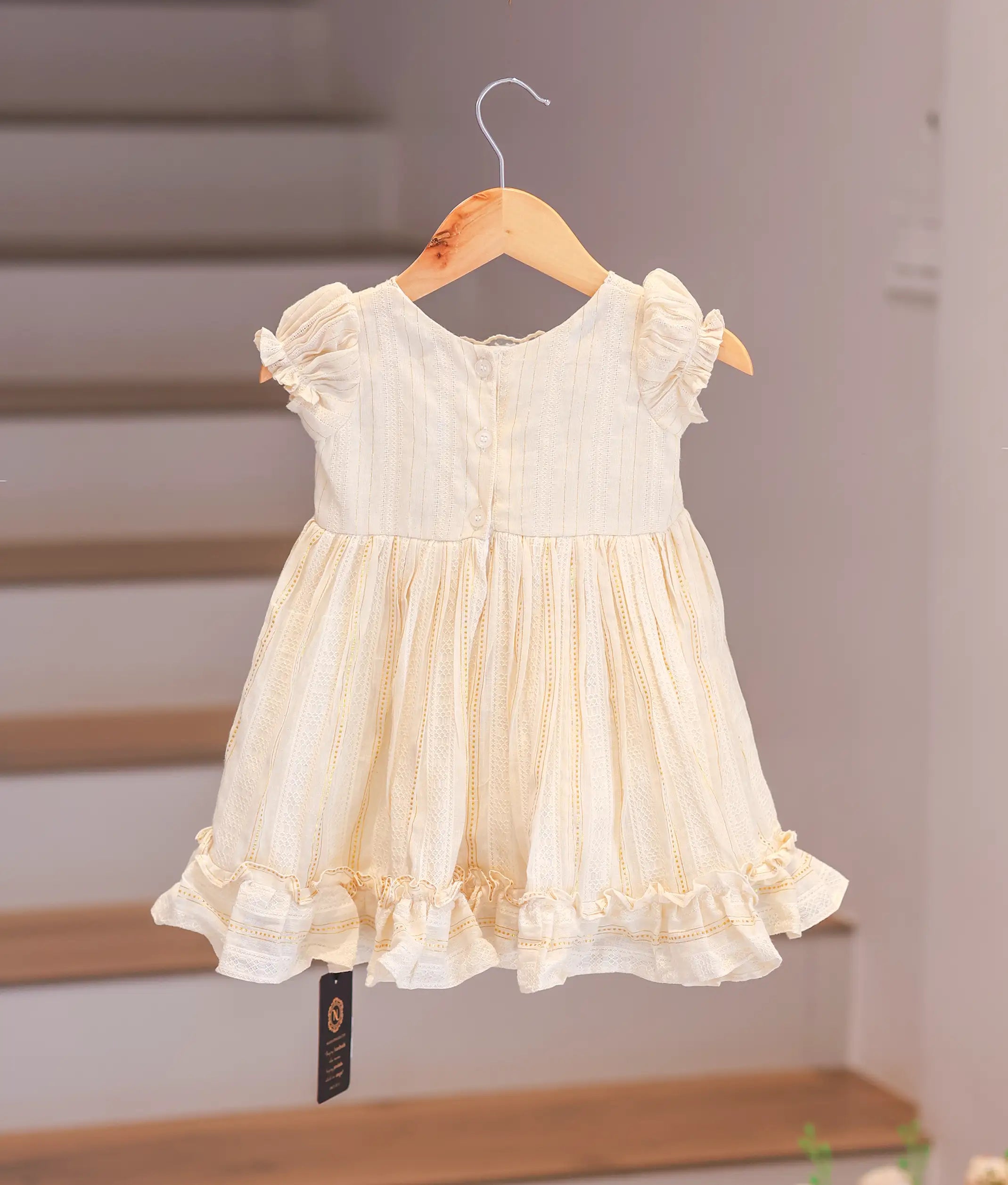 Back view of the casual cotton frock highlighting the simple button closure and adjustable waist tie