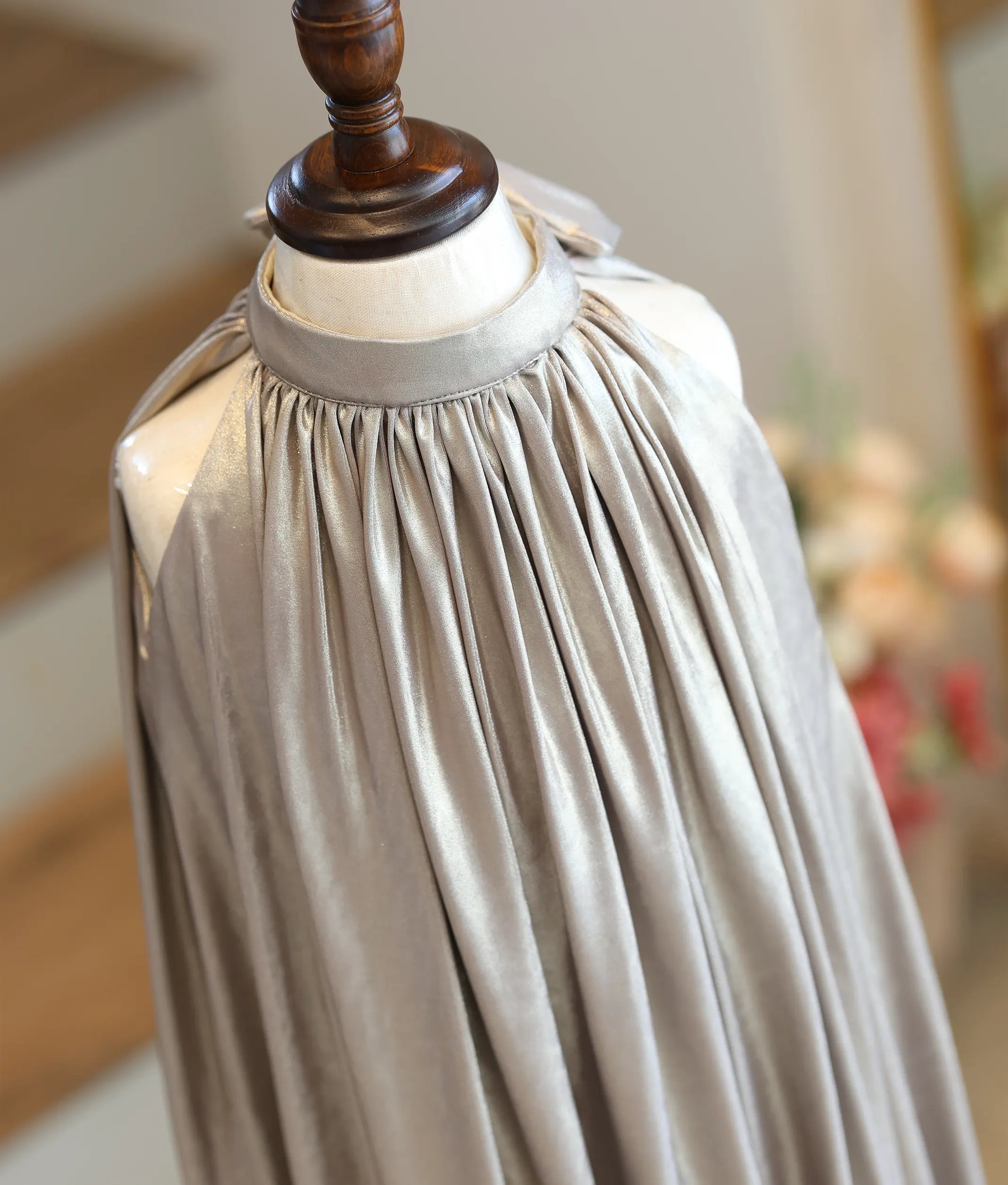 Close-up showing the sunray pleating and shimmering crinkle texture of the champagne gold fabric.