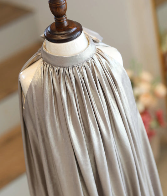 Close-up showing the sunray pleating and shimmering crinkle texture of the champagne gold fabric.