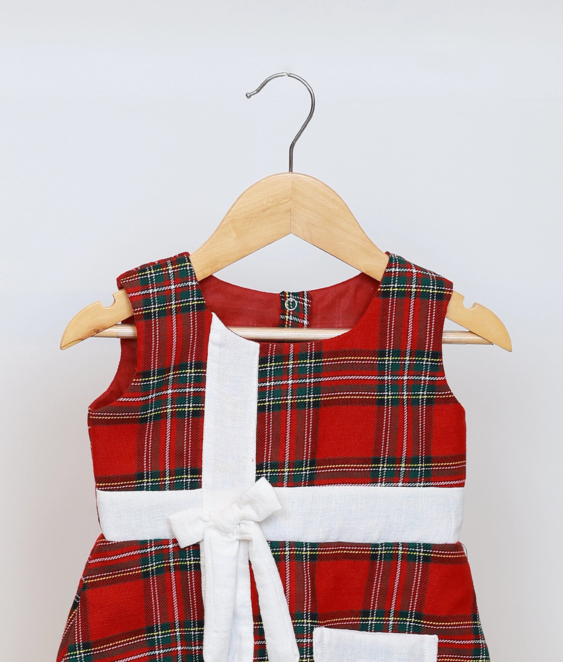 Close up of the red checkered Xmas frock showing the white gift-wrap bow and embroidered mushroom patch pocket.