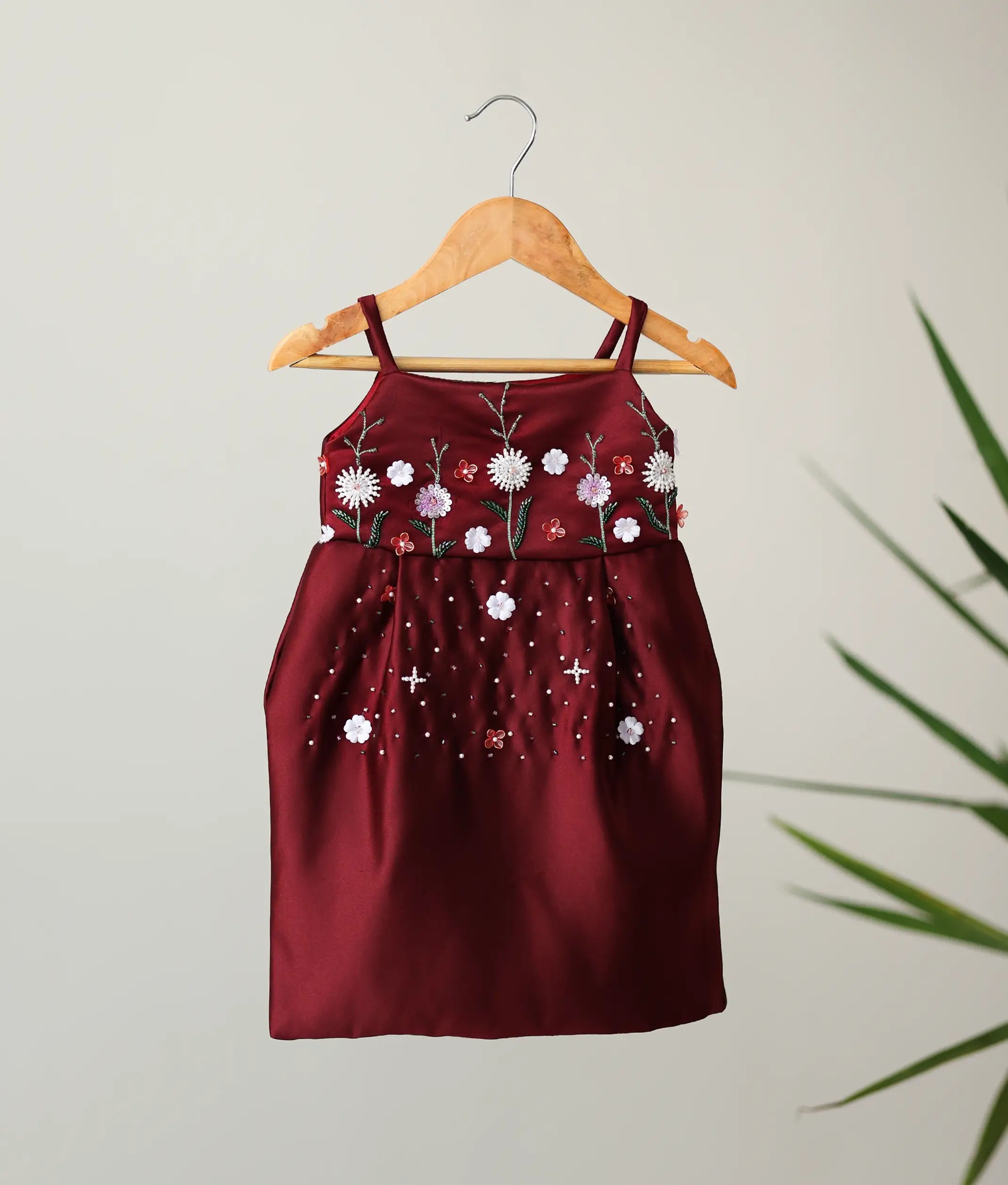 An elegant maroon bridal satin sleeveless frock with hand-embroidered floral work, the perfect choice among Christmas dresses for baby girls.