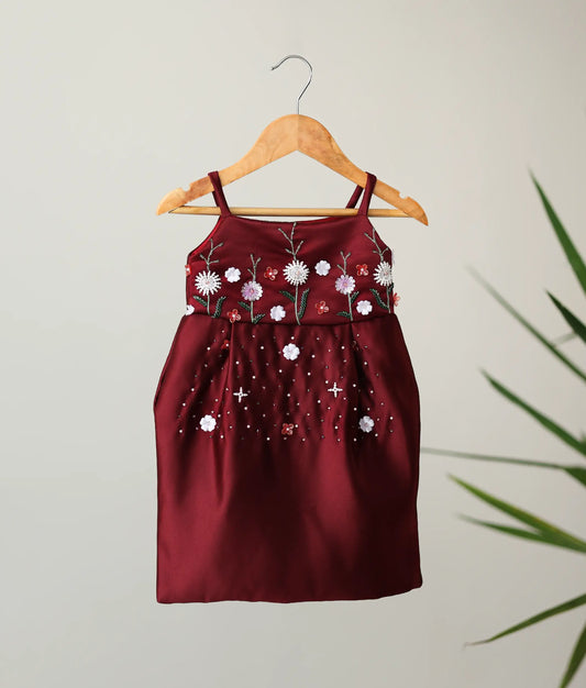 An elegant maroon bridal satin sleeveless frock with hand-embroidered floral work, the perfect choice among Christmas dresses for baby girls.