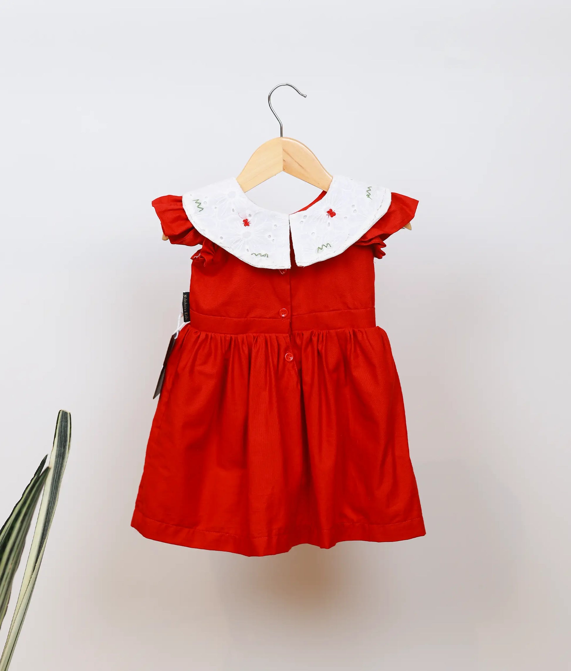 Back view of an below-knee red dress featuring a full, flared skirt and comfortable cotton fabric.