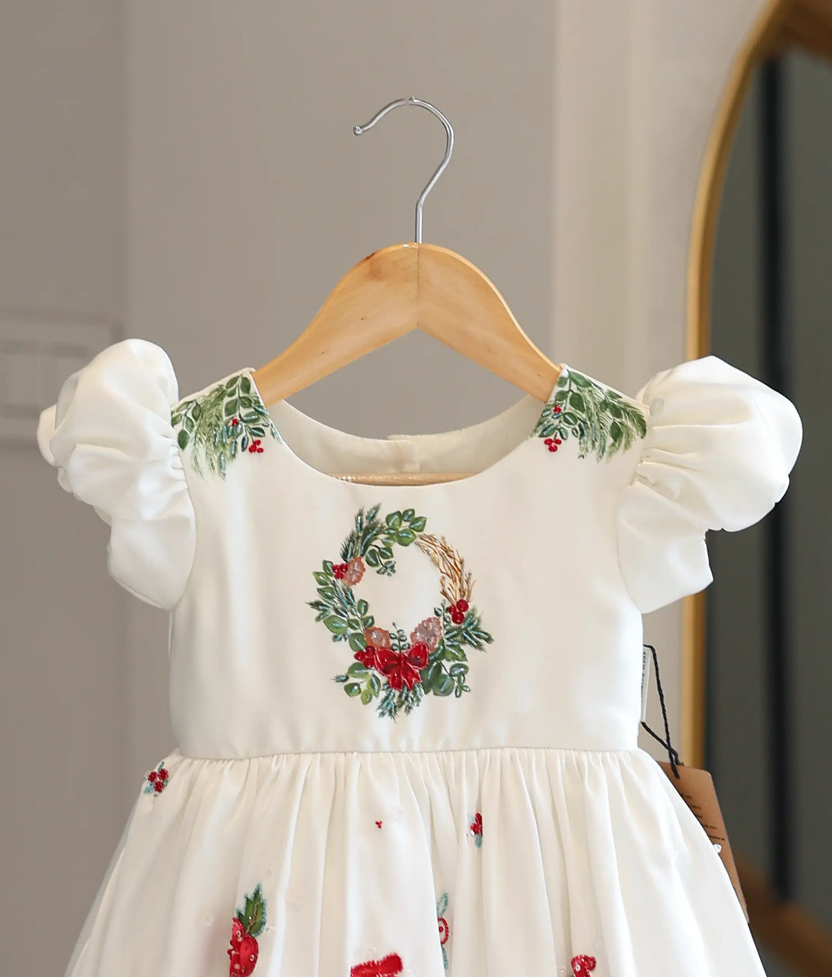 Close-up view of the bodice showing detailed Christmas wreath hand embroidery and puff sleeves.