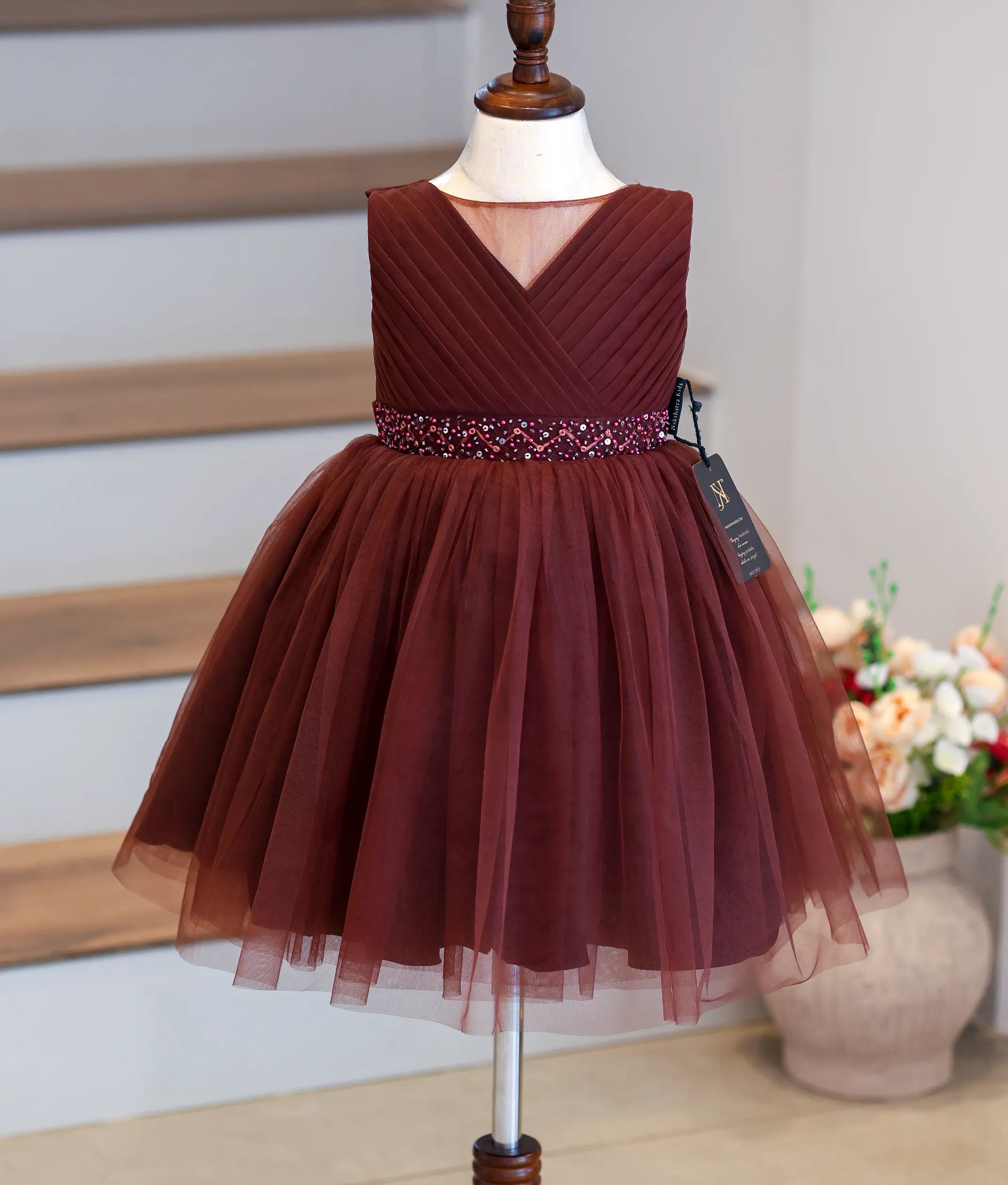 Front view of a coffee-brown flared frock for girls with a round neck net overlay.