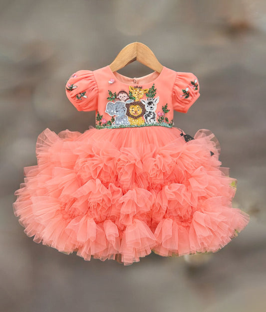 Coral orange baby girl birthday dress with puff sleeves, sequin jungle animal embroidery and handwork on the bodice, and a layered ruffled tulle skirt.
