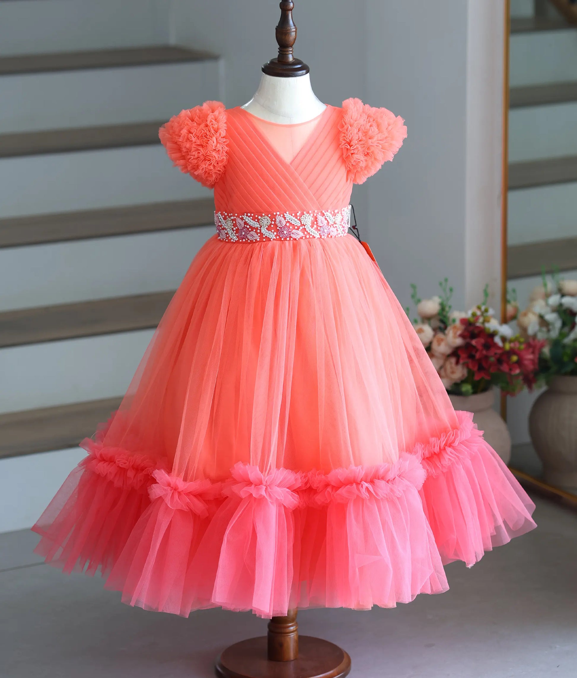 Front view of the coral peach hand-worked gown with ruffled puff sleeves.