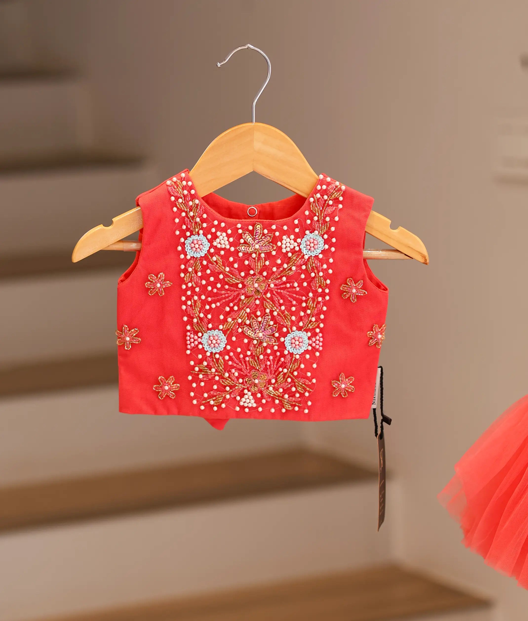 Close-up of the intricate floral handwork, sparkly beads, and matching waistband on the dark pink top