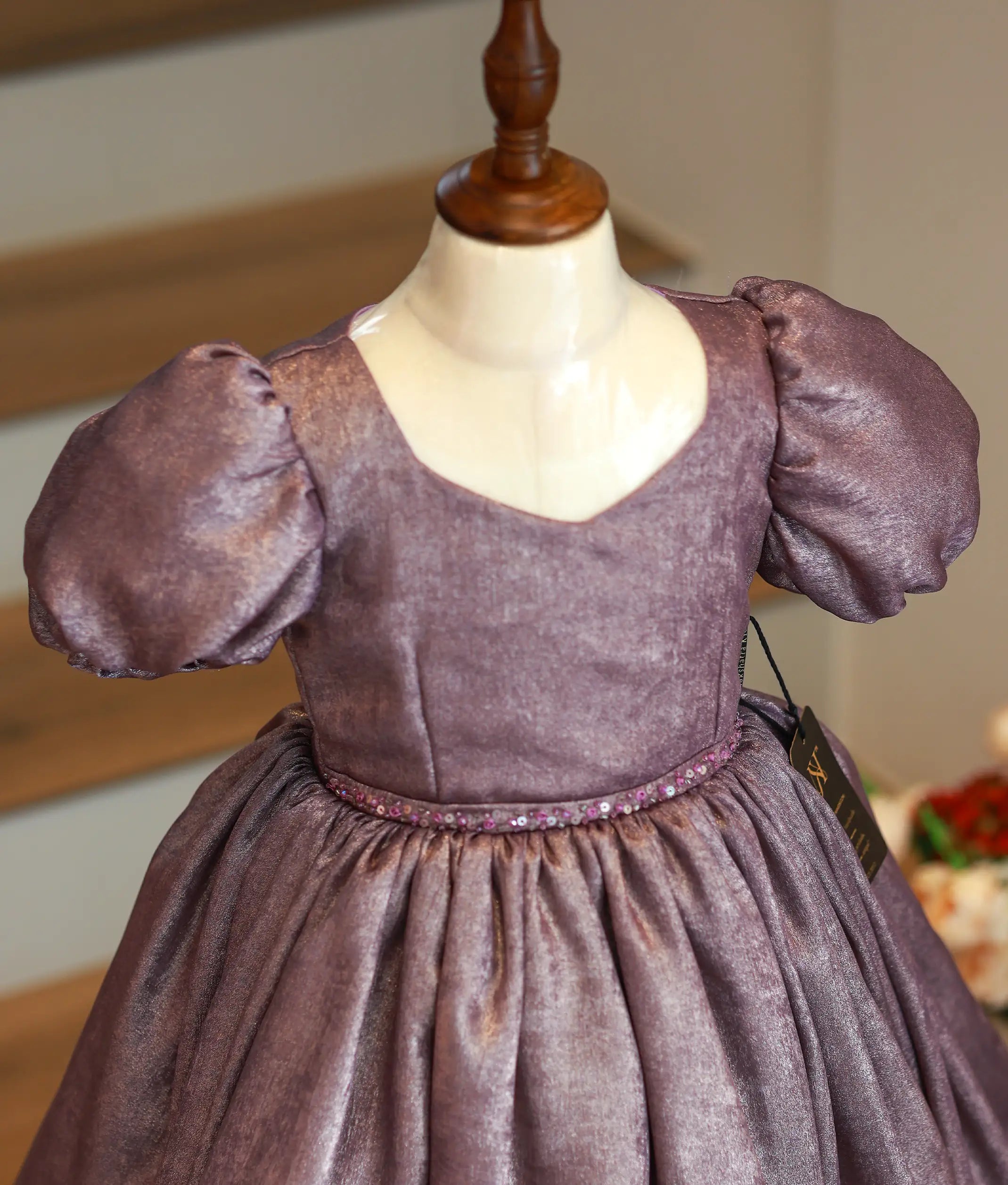 Close-up of the delicate handworked waist trim and the luminous milan foil fabric texture of the birthday frock
