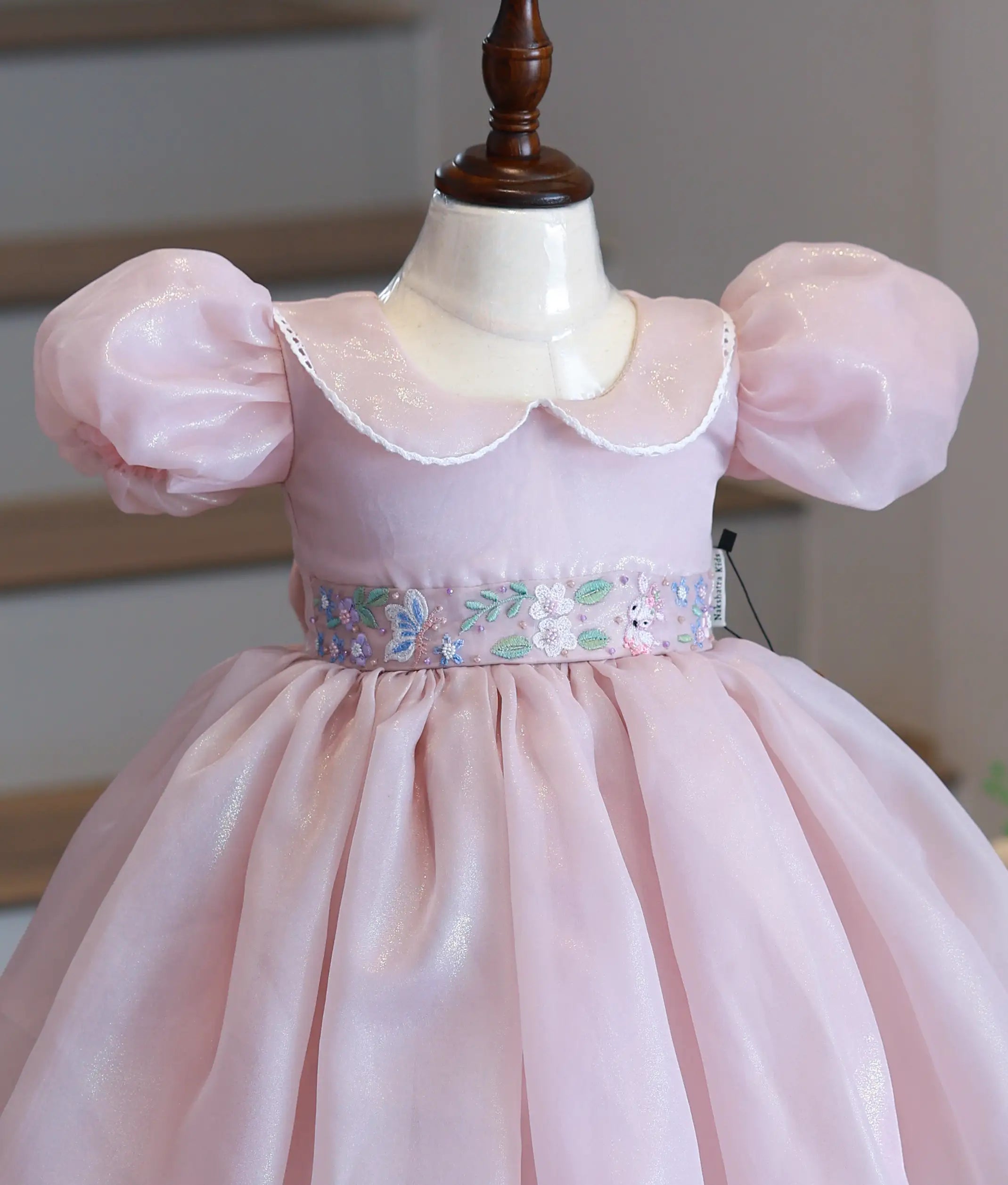 Close-up of the dusty pink bodice showing the lace-trimmed peter pan collar and intricate floral waistband embroidery