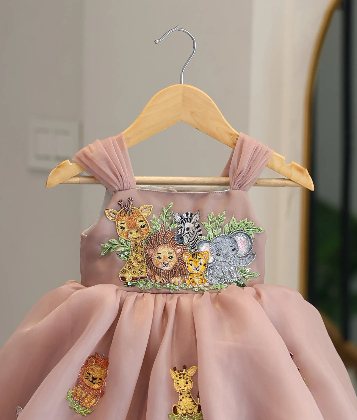 Close-up view of dusty rose frock top showing safari animal beadwork and pleated straps.