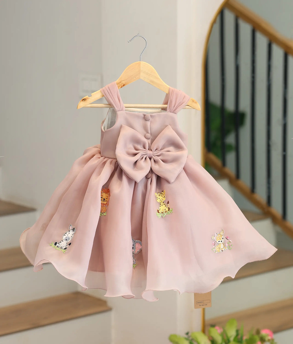 Back view of dusty rose safari theme frock showing back buttons and a bow.