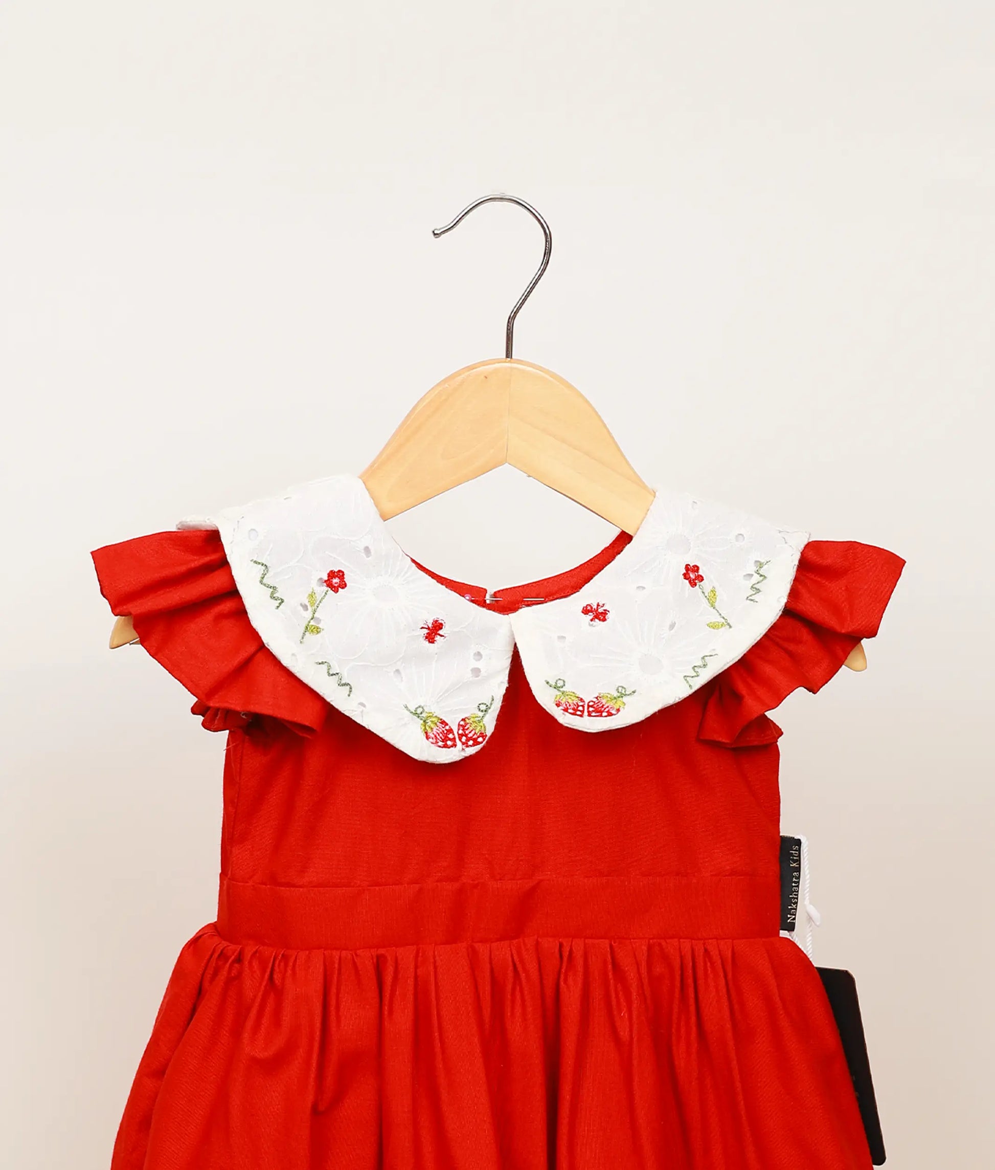 Close view of the embroidered Peter Pan collar and simple cap sleeves on the festive red dress.