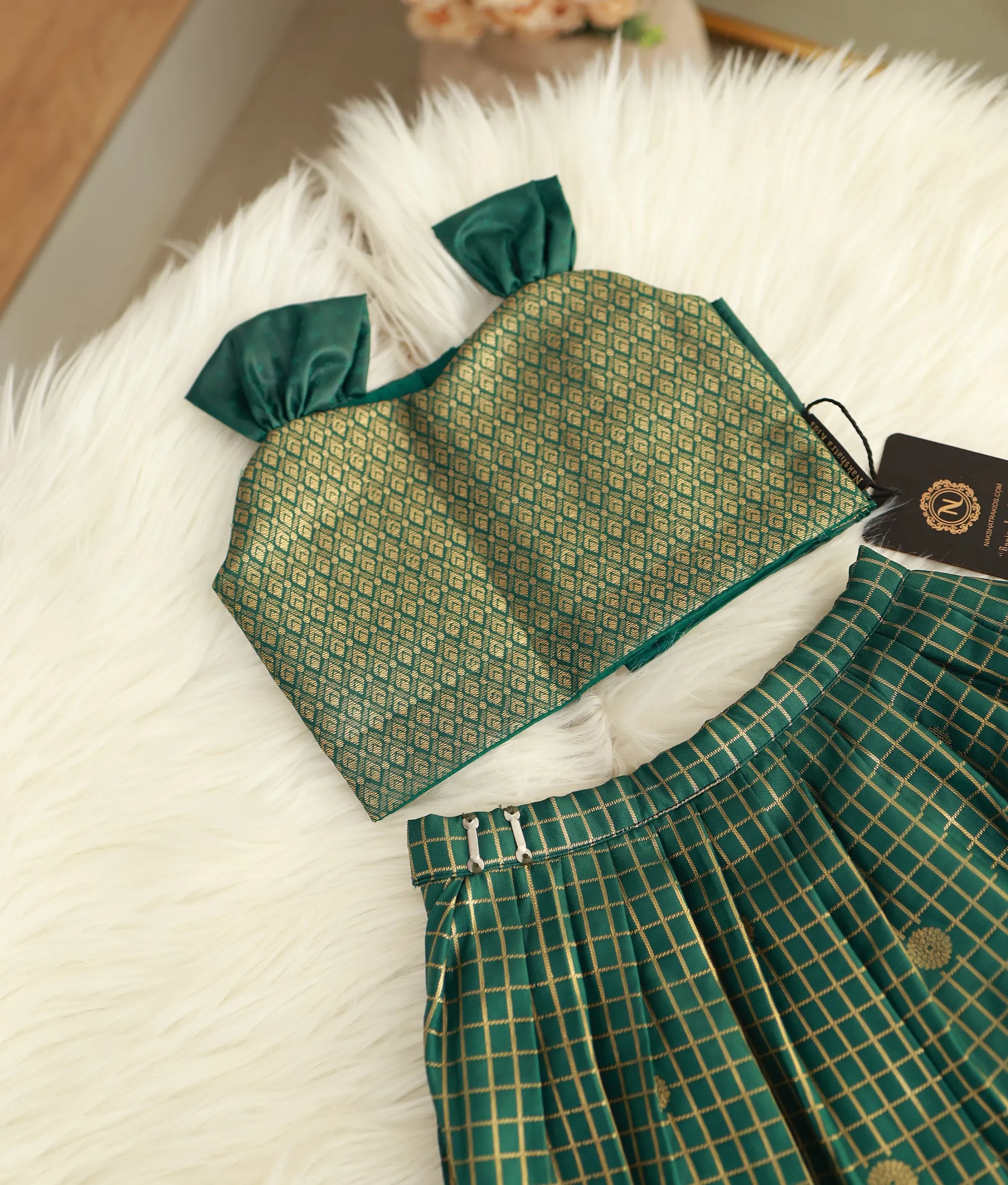 Close-up of the dense golden zari patterns on the emerald green silk bodice.