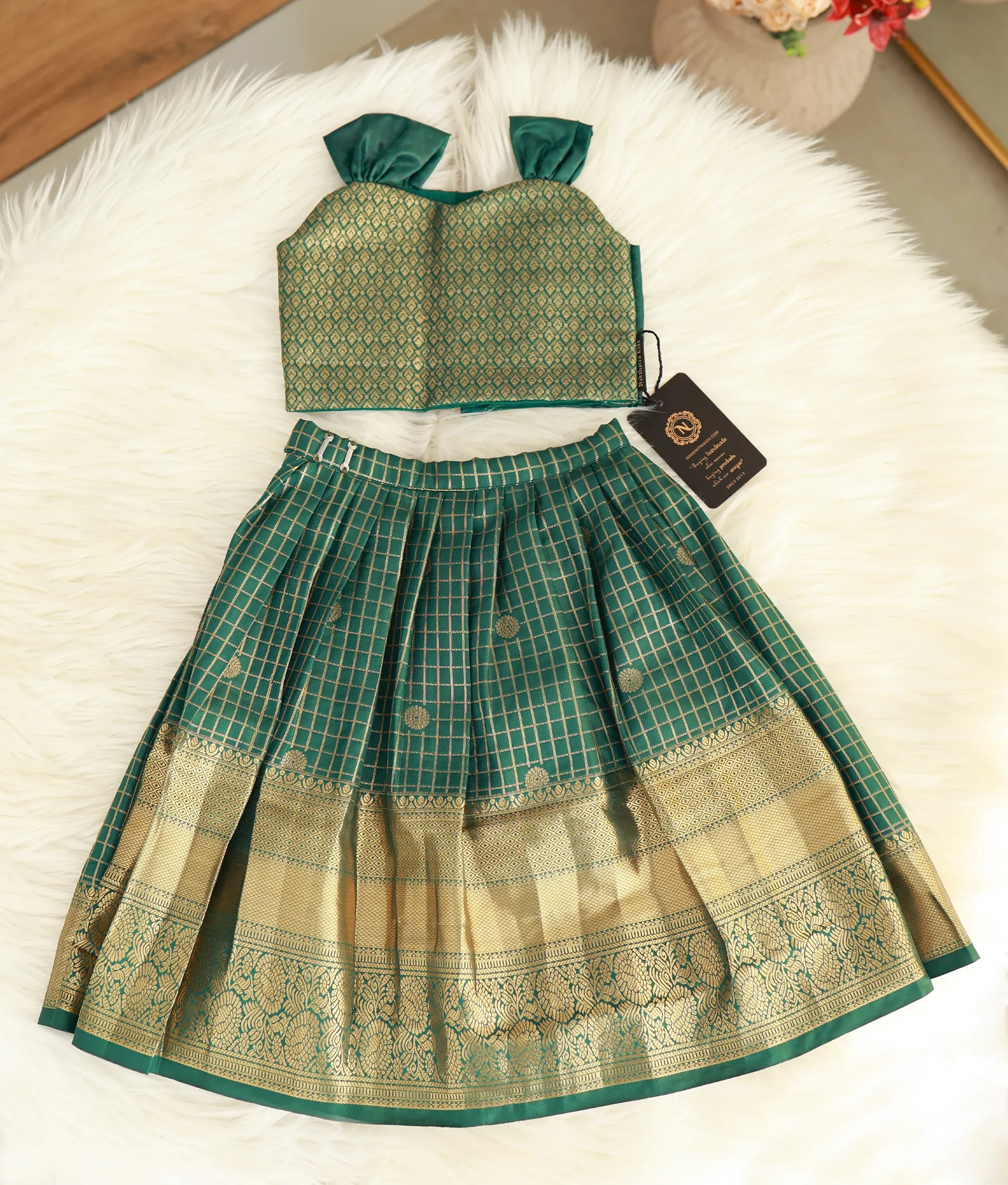 Front view of a girls' emerald green Kanchipuram silk skirt and top with golden zari checks and a wide border.