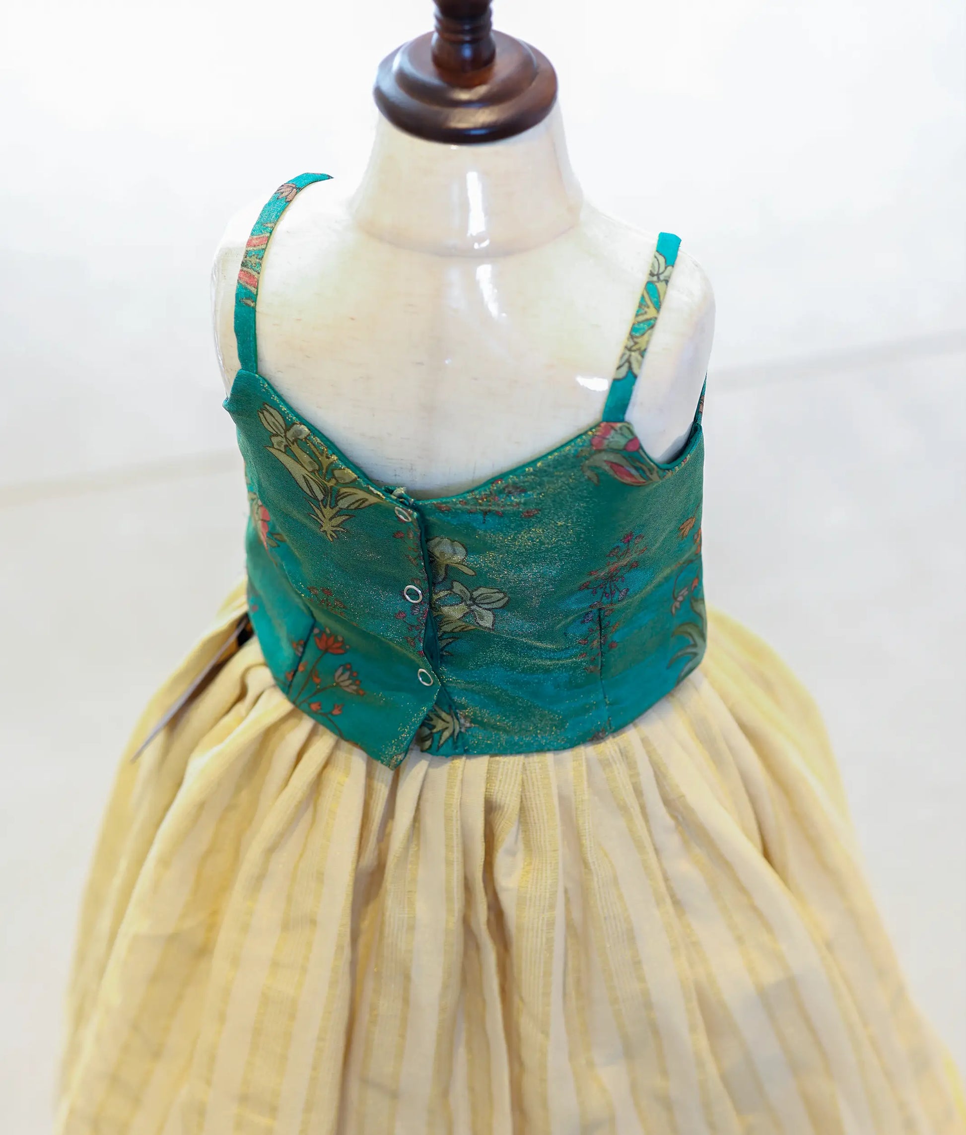 Back view of the emerald green top showing the row of secure button closures.