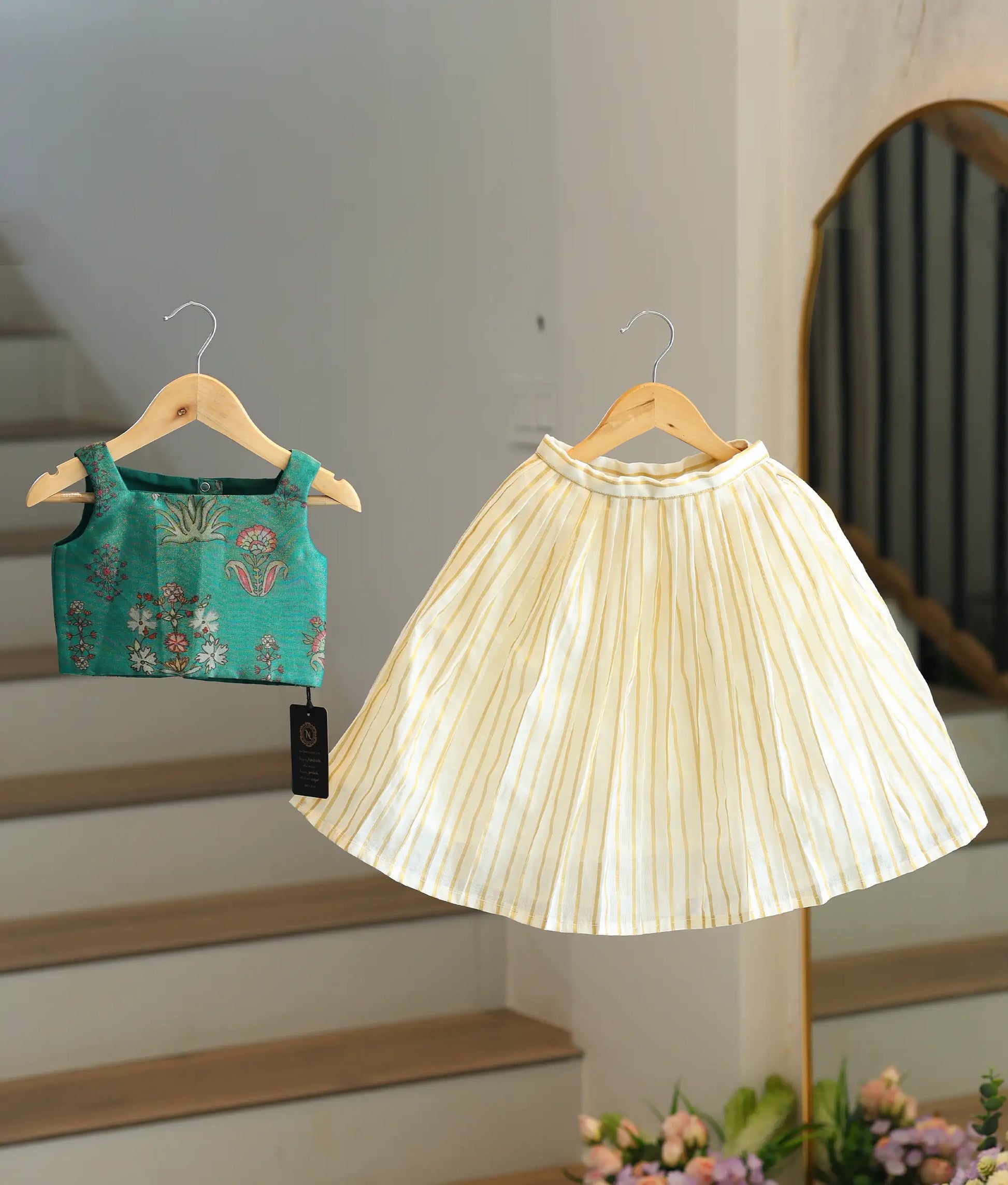 Front view of a girls' emerald green woven top and pleated skirt set
