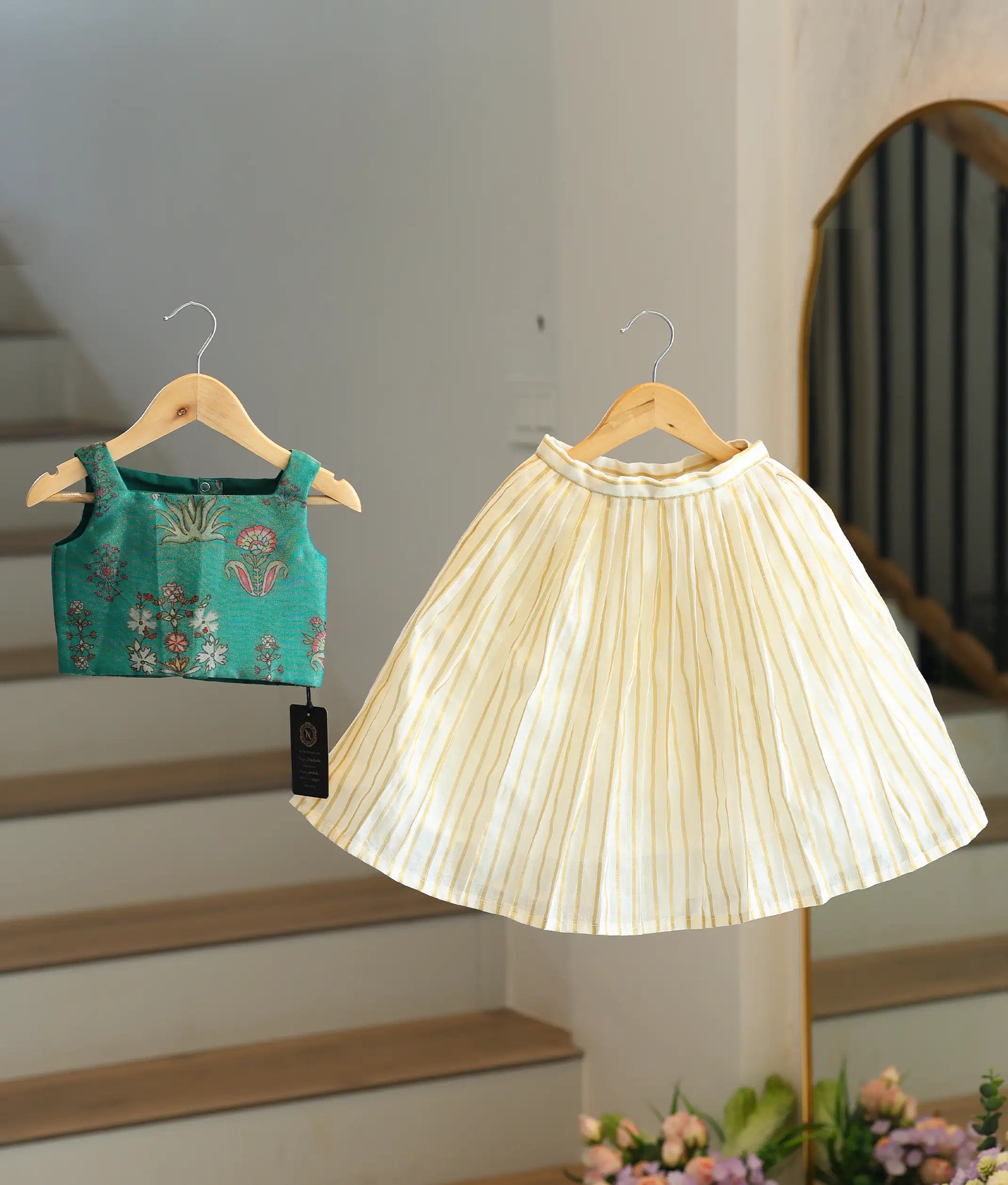 Front view of a girls' emerald green woven top and pleated skirt set