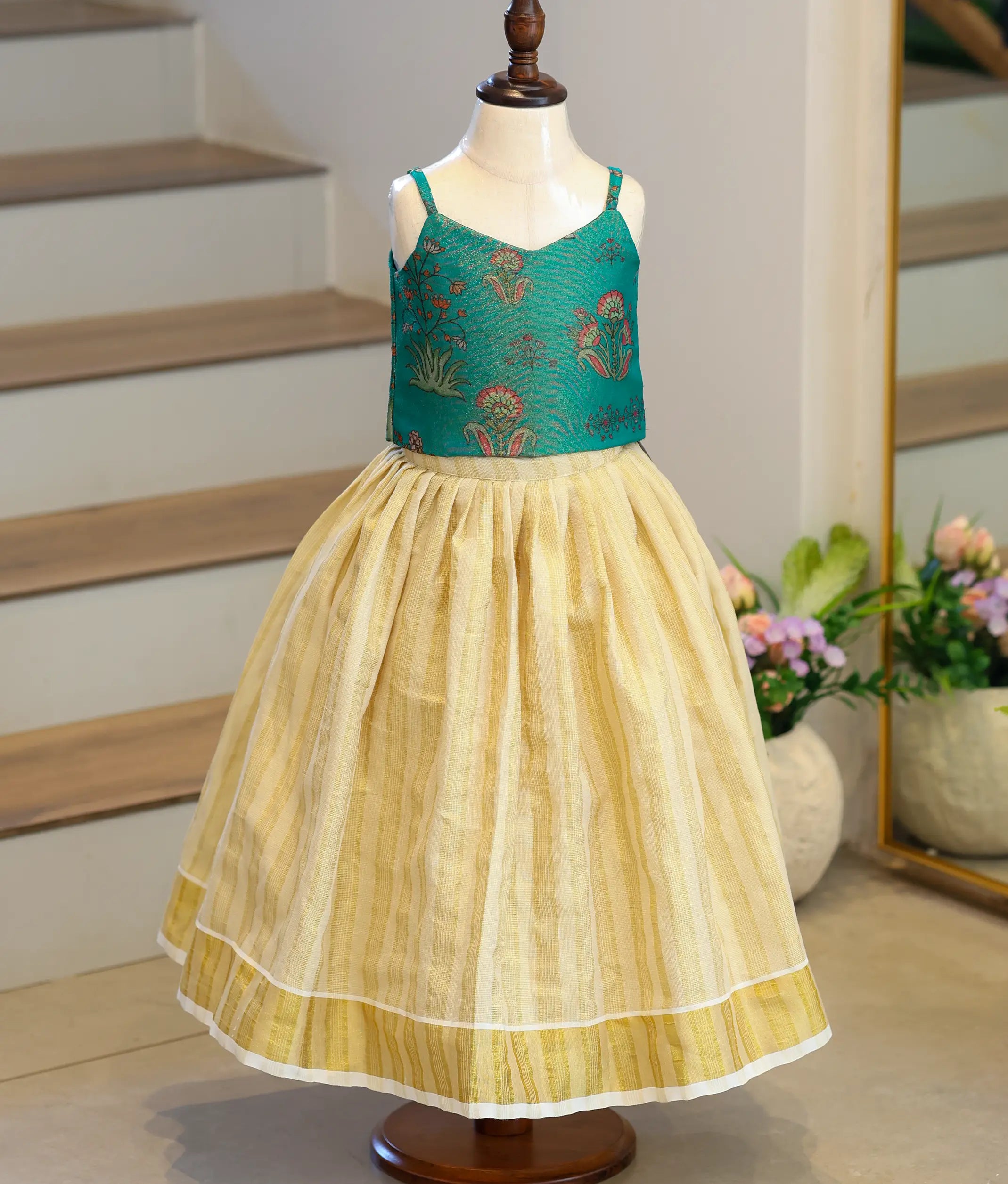 Front view of a girls' emerald green woven top and pleated skirt set.