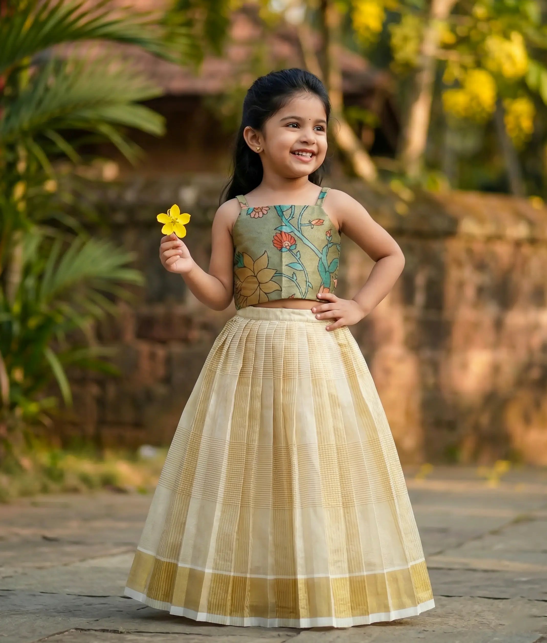 Baby girl wearing a traditional-style olive green floral silk top with a kasavu-checked frock.