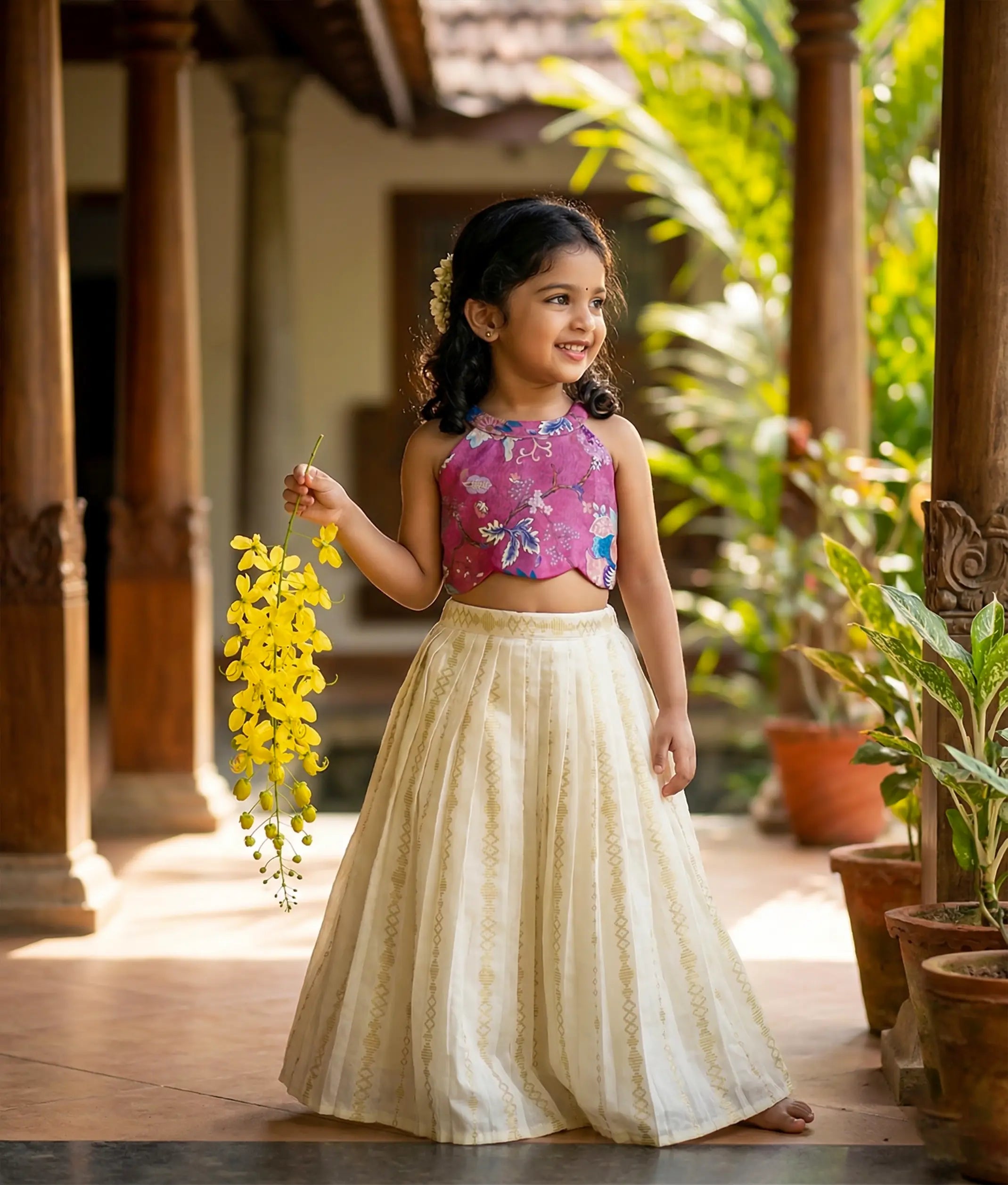 Baby girl wearing a traditional-style onion-pink floral silk top with a kasavu striped frock.