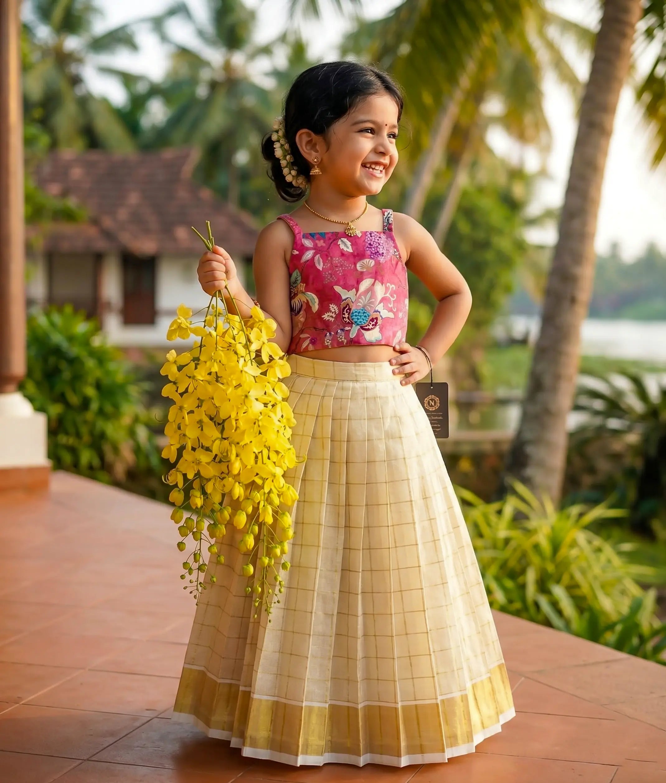 Baby girl wearing a traditional-style onion-pink floral silk top with a kasavu-checked frock.