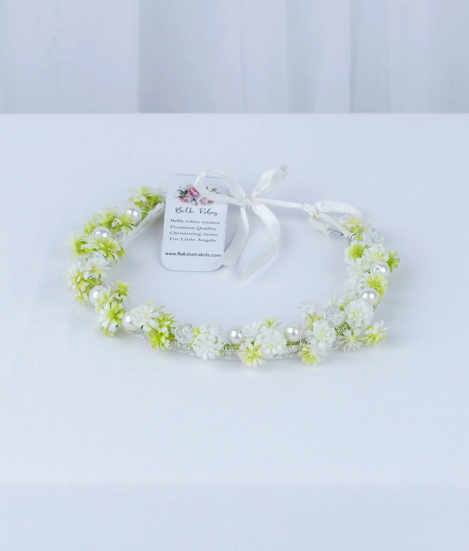 Close-up of premium fabric flowers and green leaf accents on a boutique baby girl baptism hair accessory.