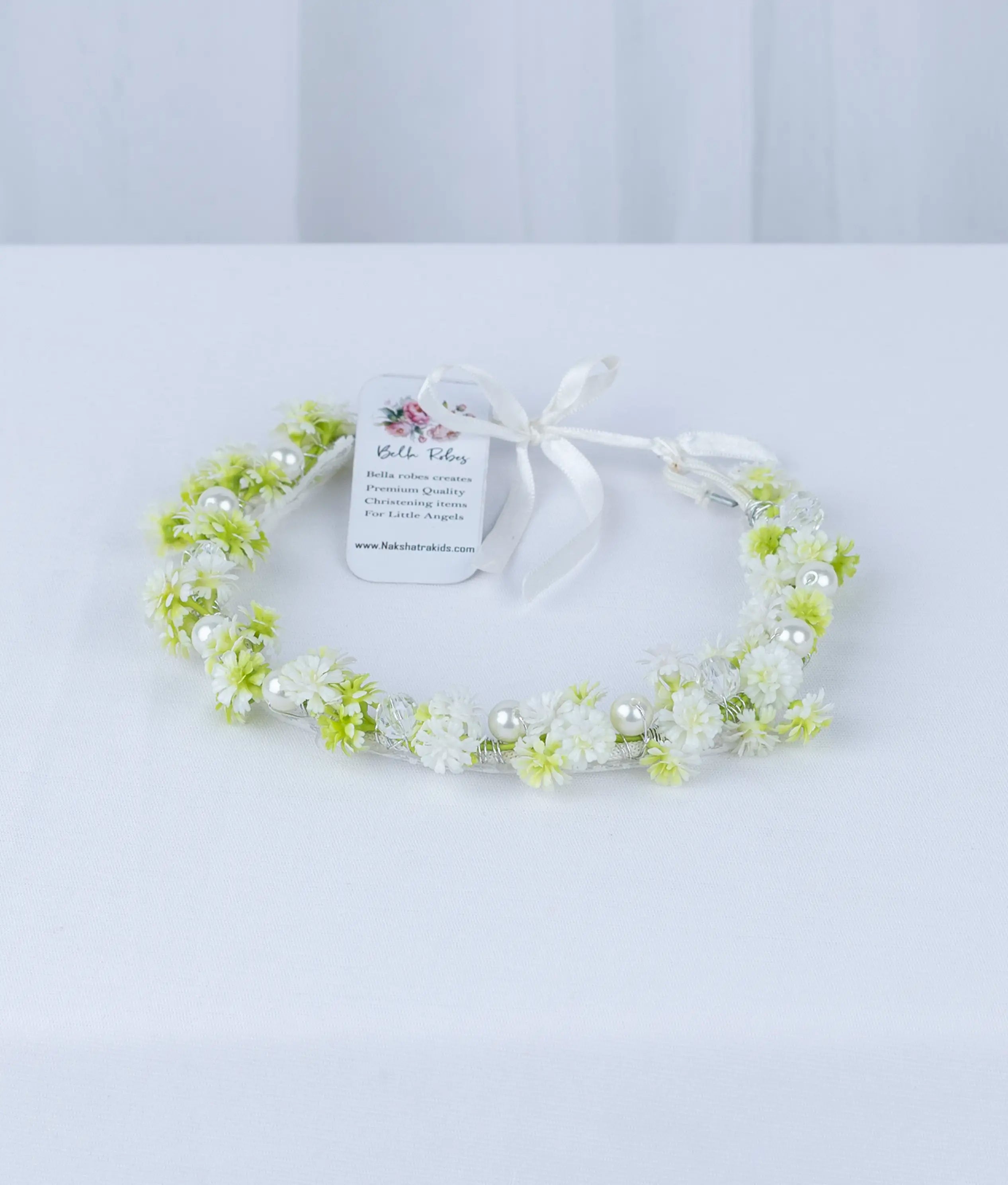 Close-up of premium fabric flowers and green leaf accents on a boutique baby girl baptism hair accessory.