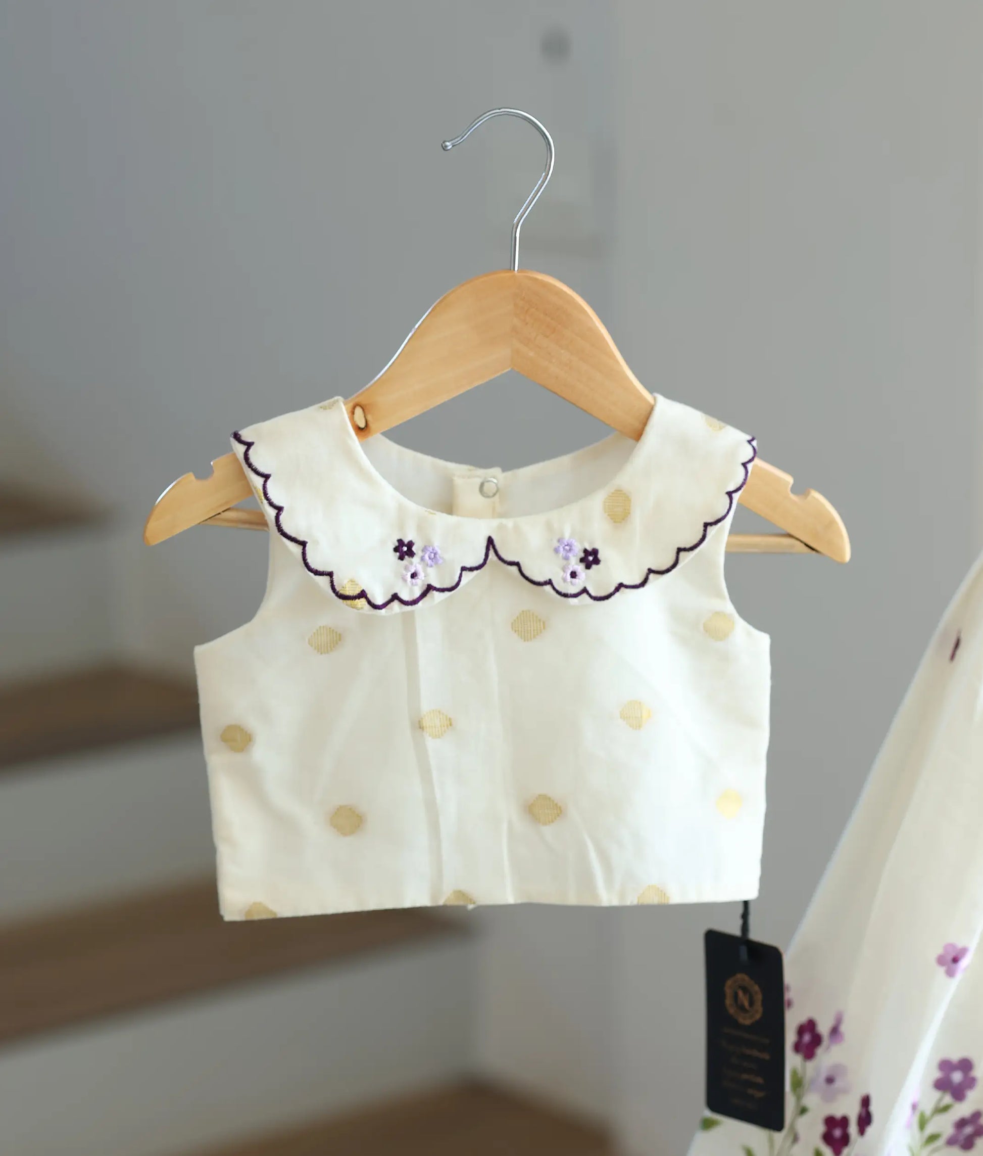 Close-up of lavender floral embroidery and peter pan collar on the off-white top.