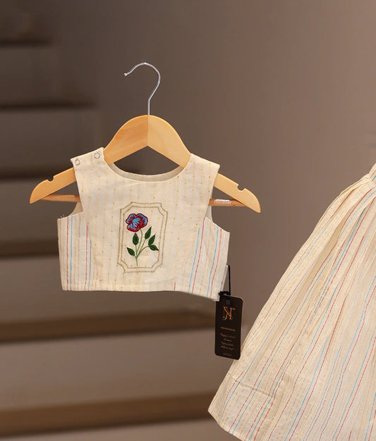 Close-up of the handcrafted pink and green floral embroidery on the off-white cotton fabric