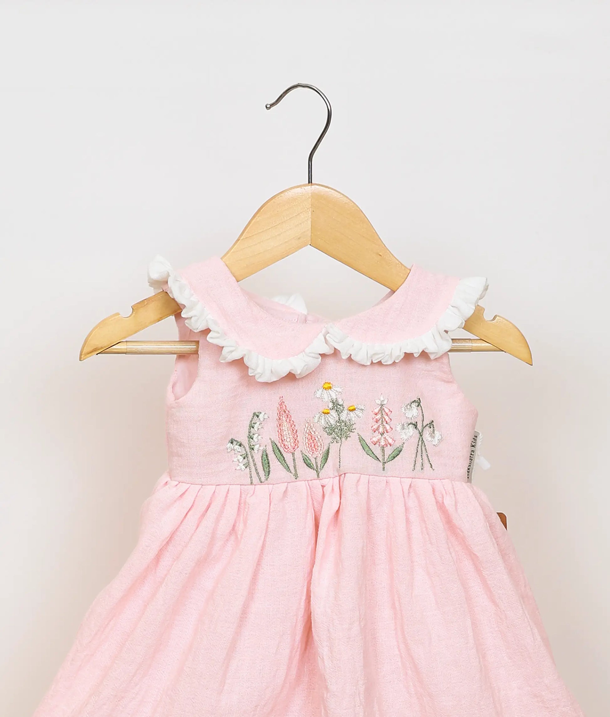 Close view of an Peter Pan collar and floral embroidery detail on the sleeveless pink dress.