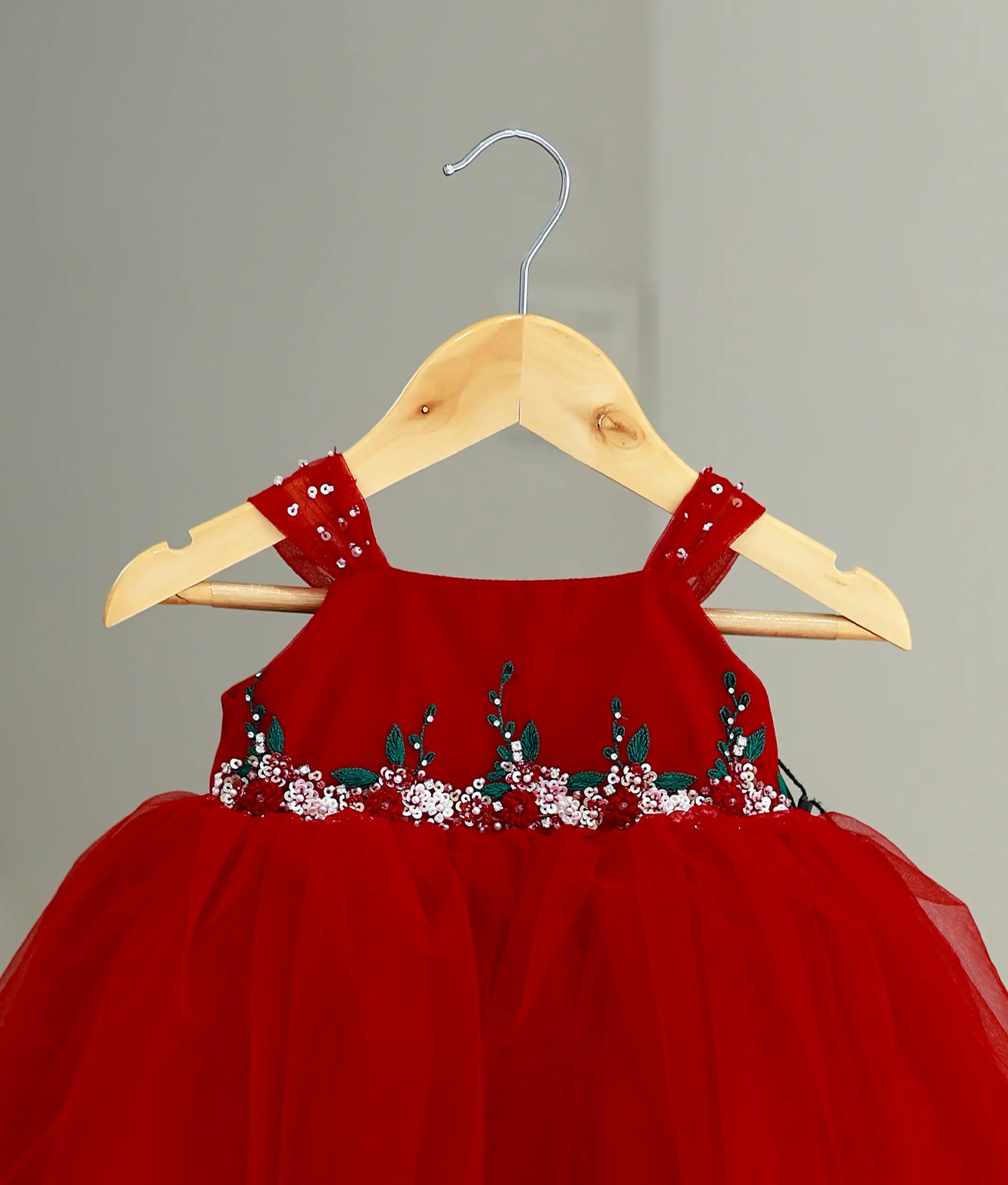Close up of floral embroidery and pink sequins on the bodice of the red party wear frock.