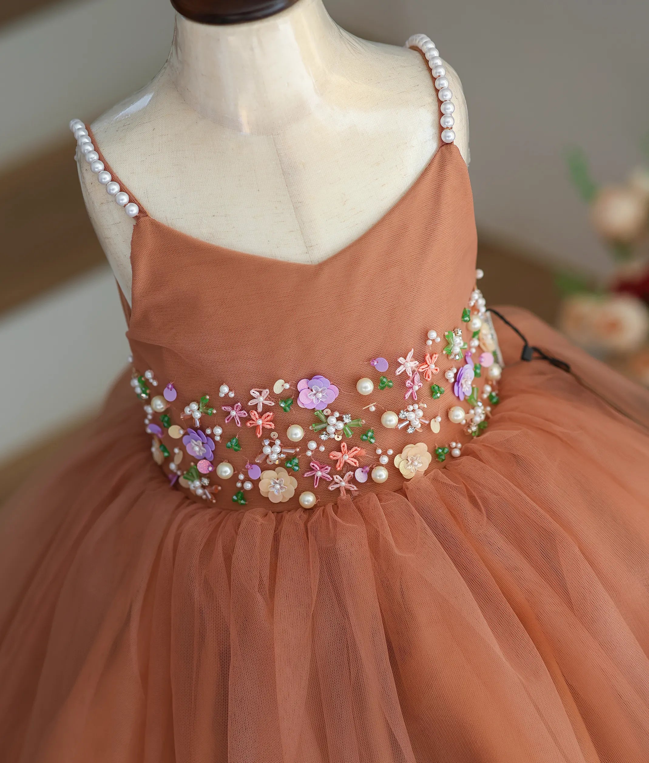 Close-up of the intricate pearls, beads, and thread handwork on the dusty peach frock.