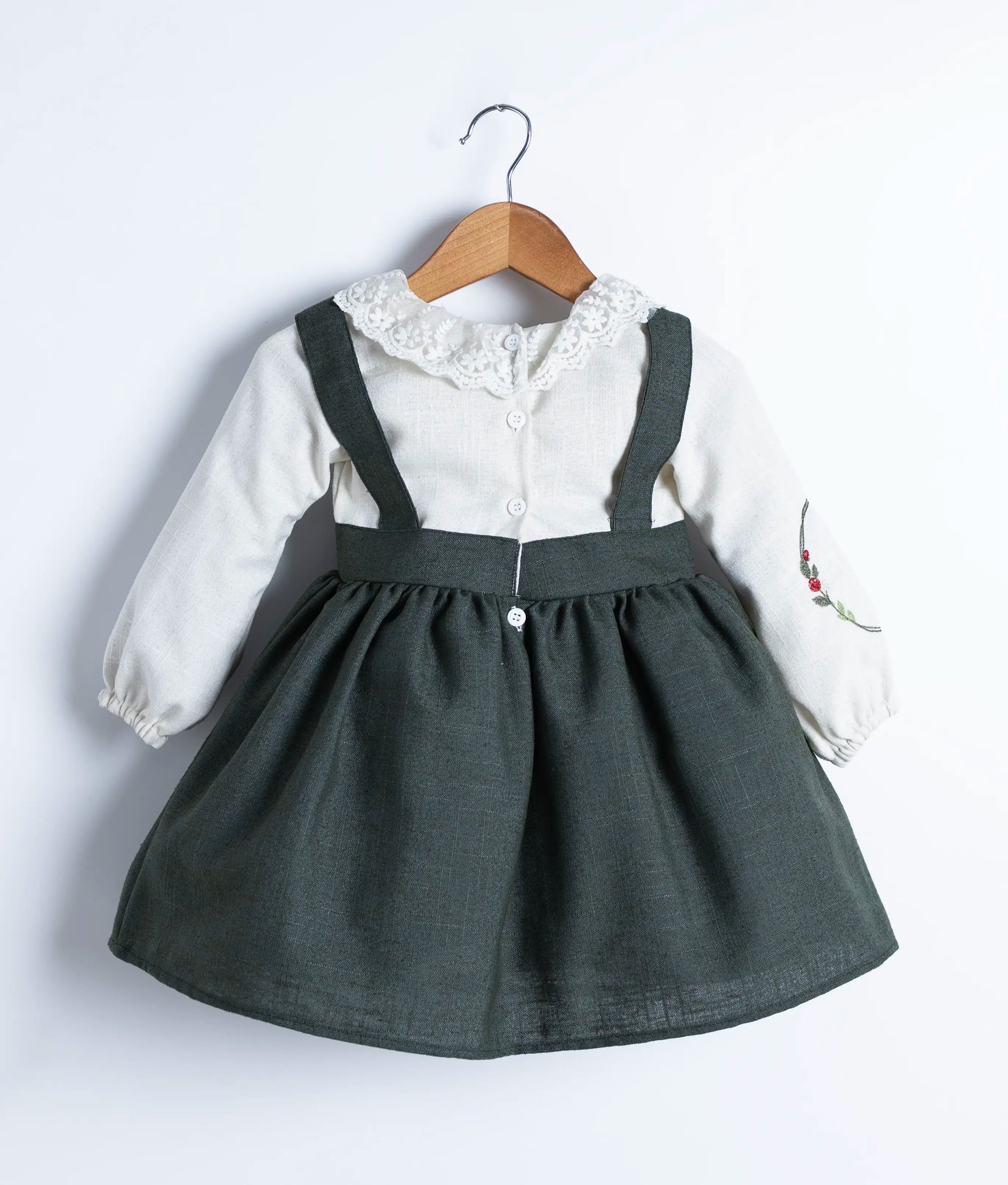 Knee-length view of the flowing green skirt, gathered at the waist of the festive linen dress