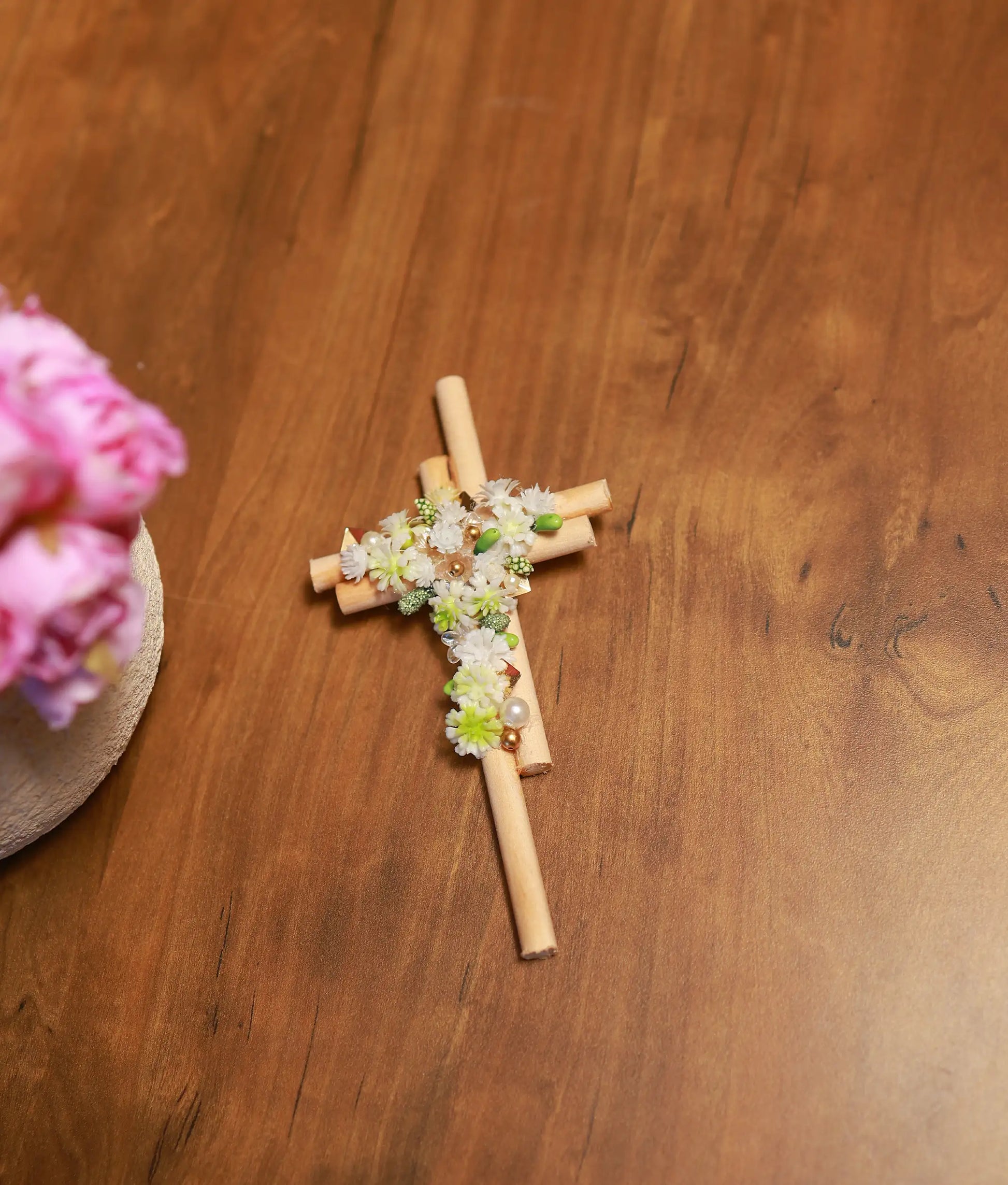 Front view of a handcrafted wooden cross featuring white and green floral clusters with pearl and gold bead accents