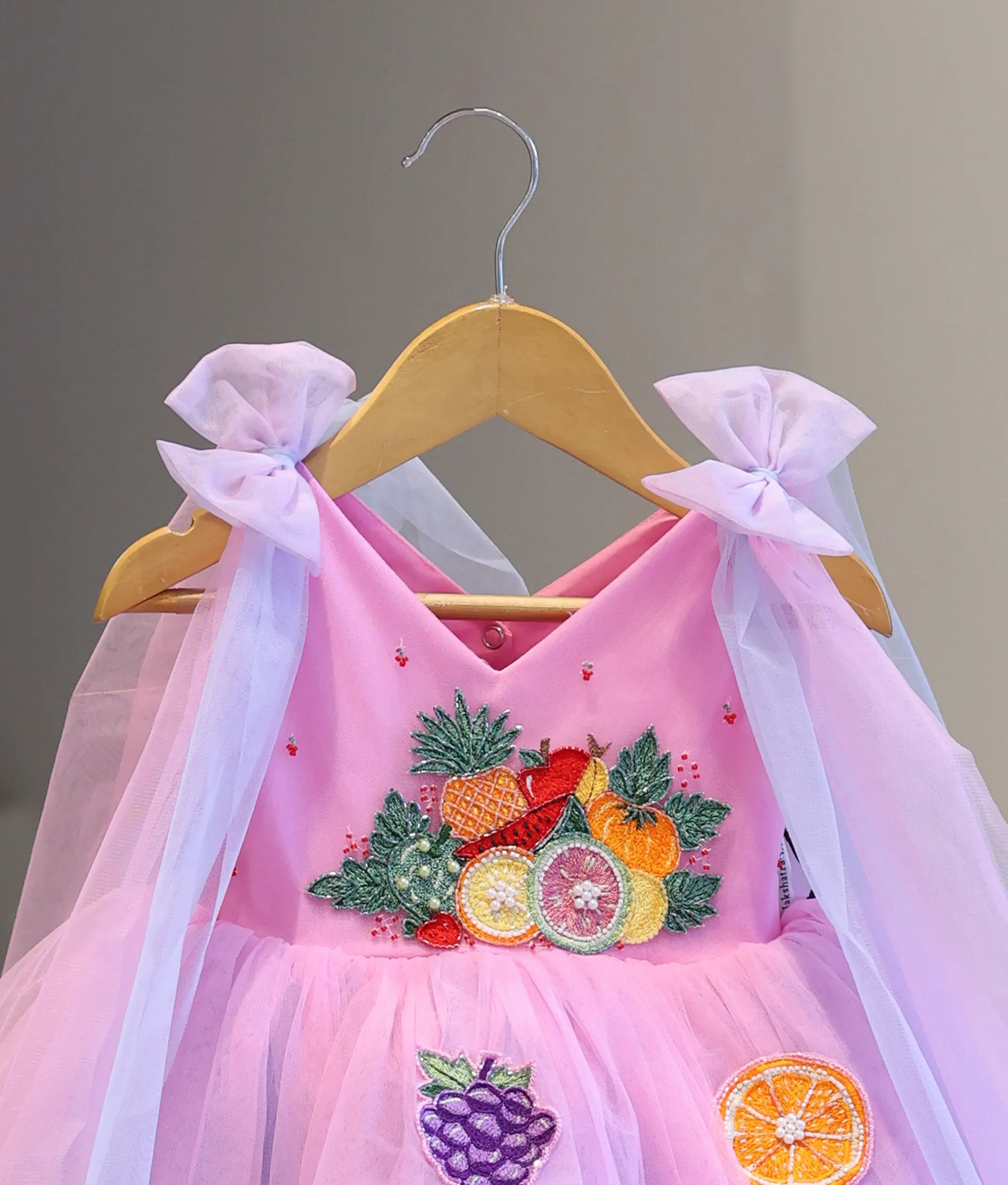 Close-up of pink girl's party dress featuring handcrafted fruit embroidery, V-neck bodice and layered tulle design
