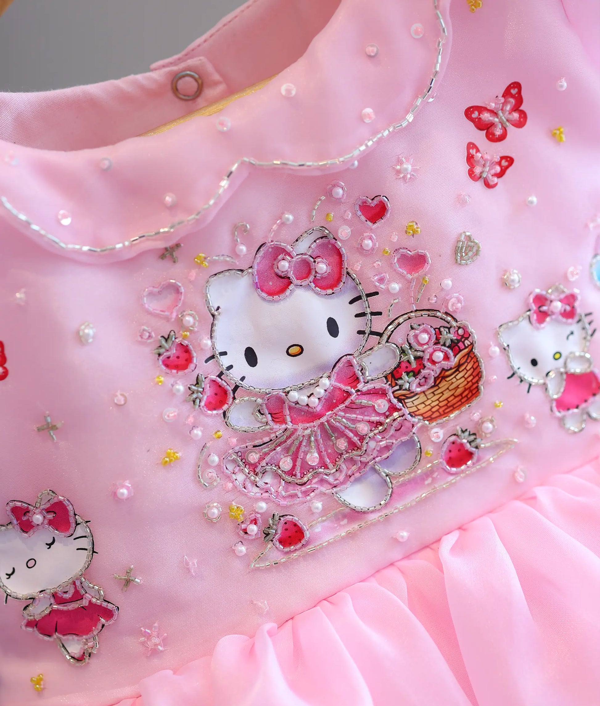 Detailed close-up of intricate handworked beads, pearls, and sequins on the Hello Kitty bodice motif.