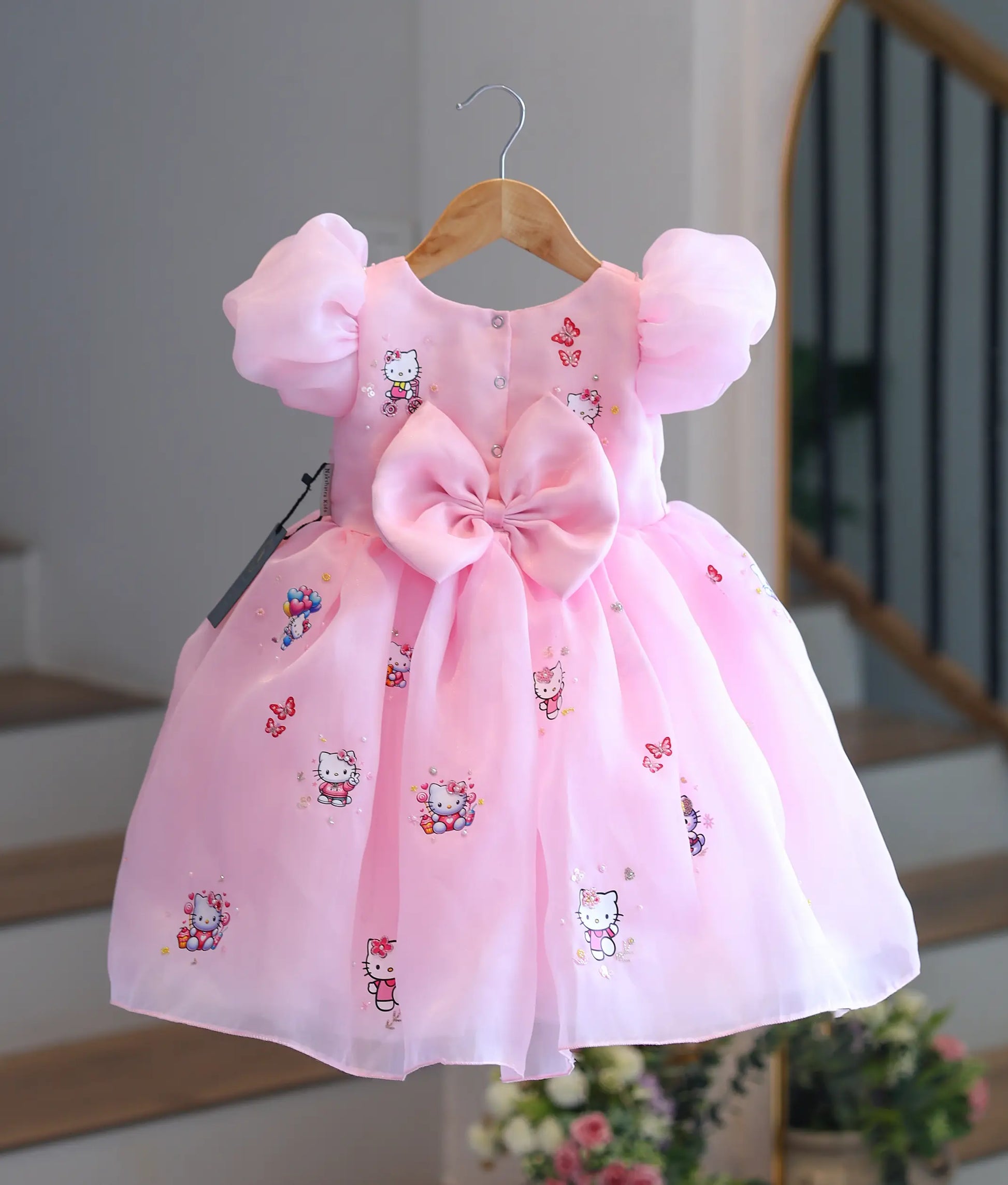 Back view of baby pink Hello Kitty organza frock showing snap button closure and statement bow.