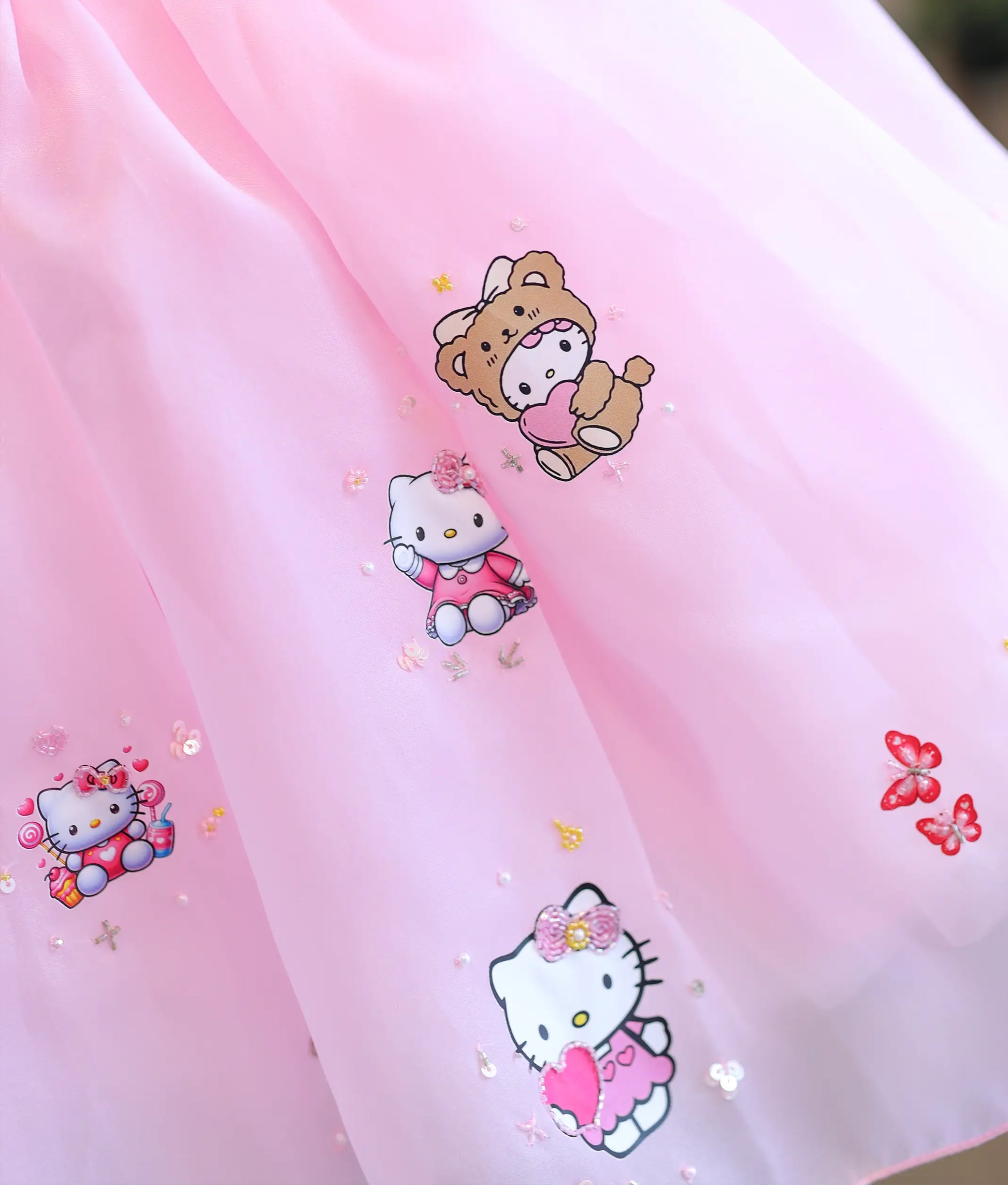 Detail view of organza flare with printed Hello Kitty, teddy bear, and sequin accents.