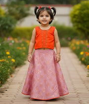 Front view of the traditional two-piece set featuring an orange handworked top and pink Banarasi silk skirt for girls