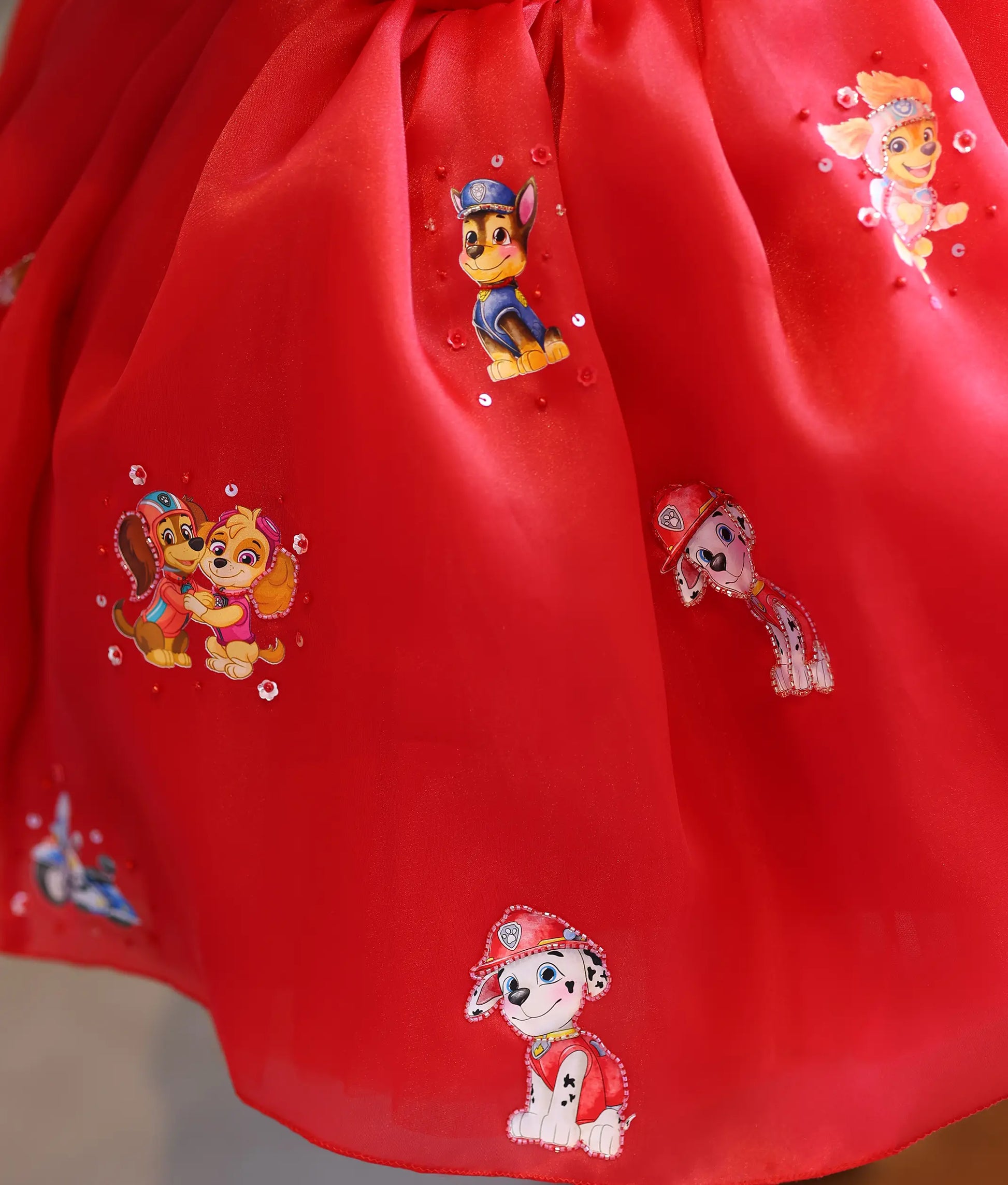 Detailed view of the red organza bottom flared skirt with Paw Patrol character prints and sequin embellishments.