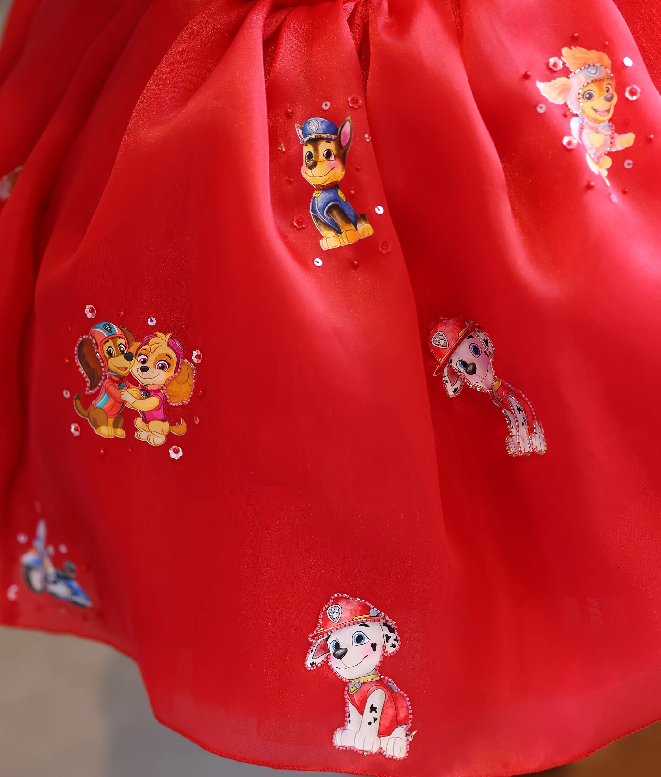 Detailed view of the red organza bottom flared skirt with Paw Patrol character prints and sequin embellishments.