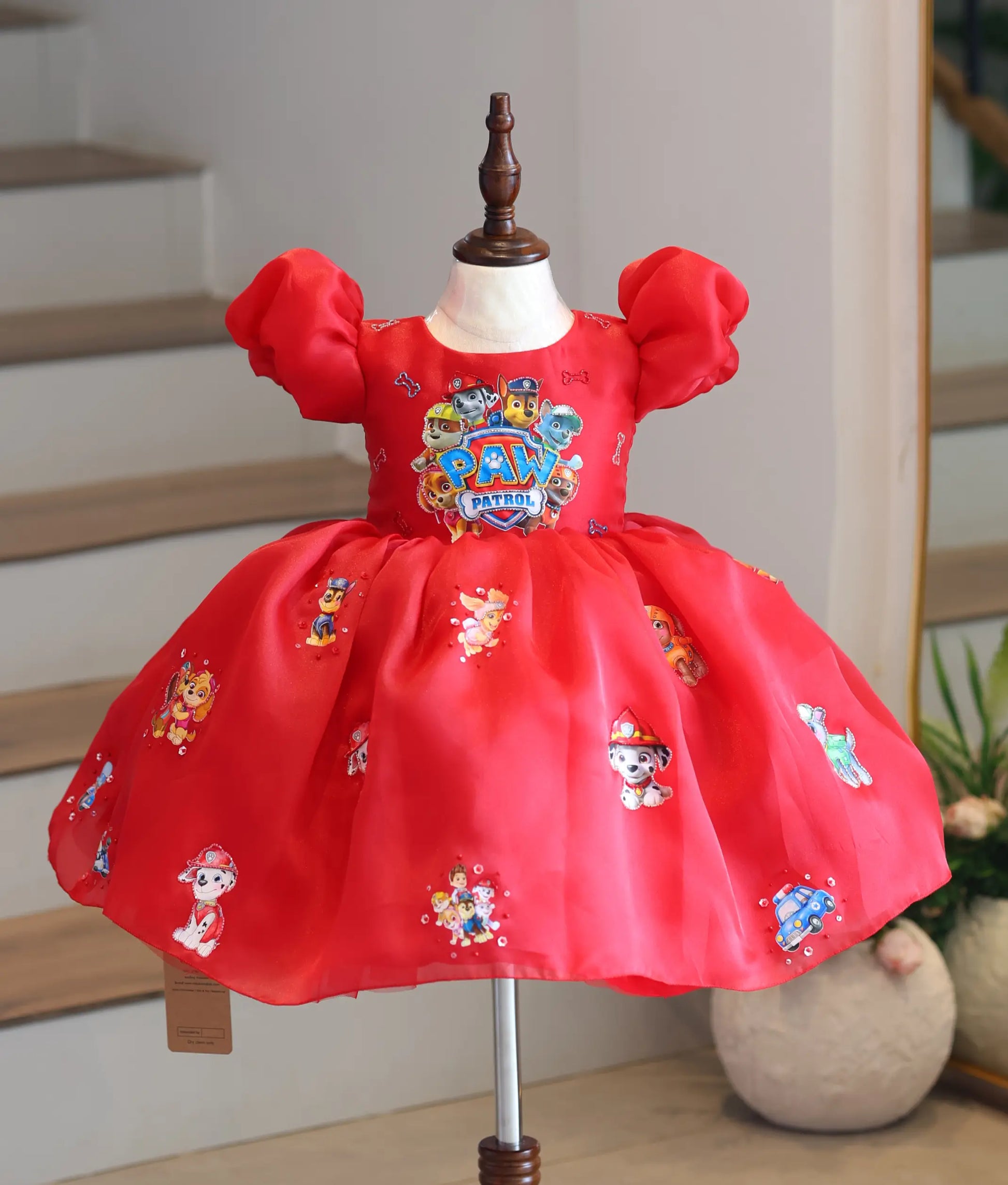 Front view of a bright red organza Paw Patrol theme party frock for girls on a mannequin display.