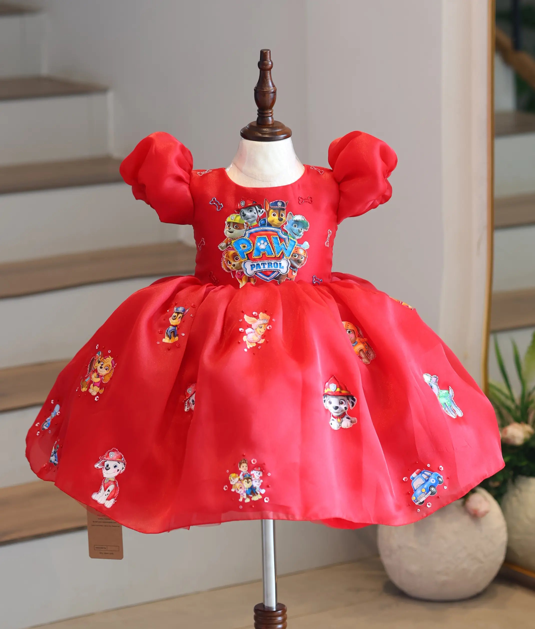 Front view of a bright red organza Paw Patrol theme party frock for girls on a mannequin display.