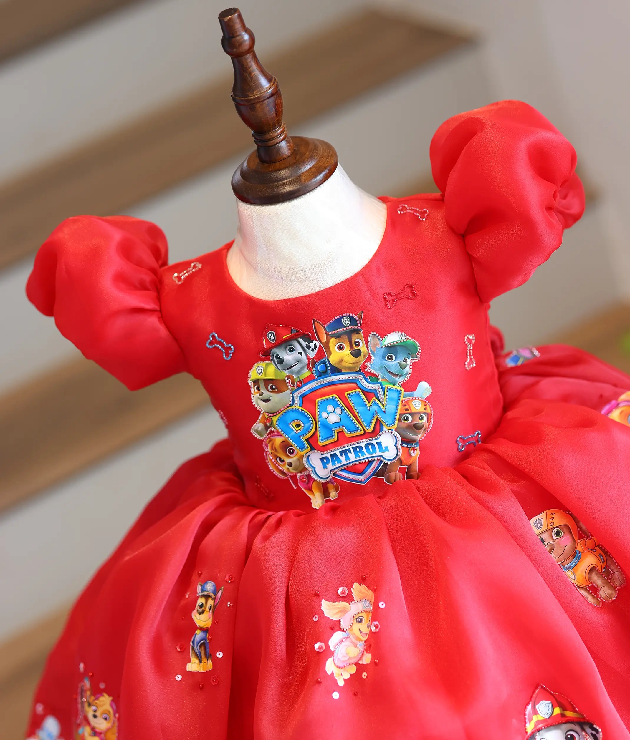 Close-up of the red organza frock top showing the Paw Patrol group graphic and puff sleeves.