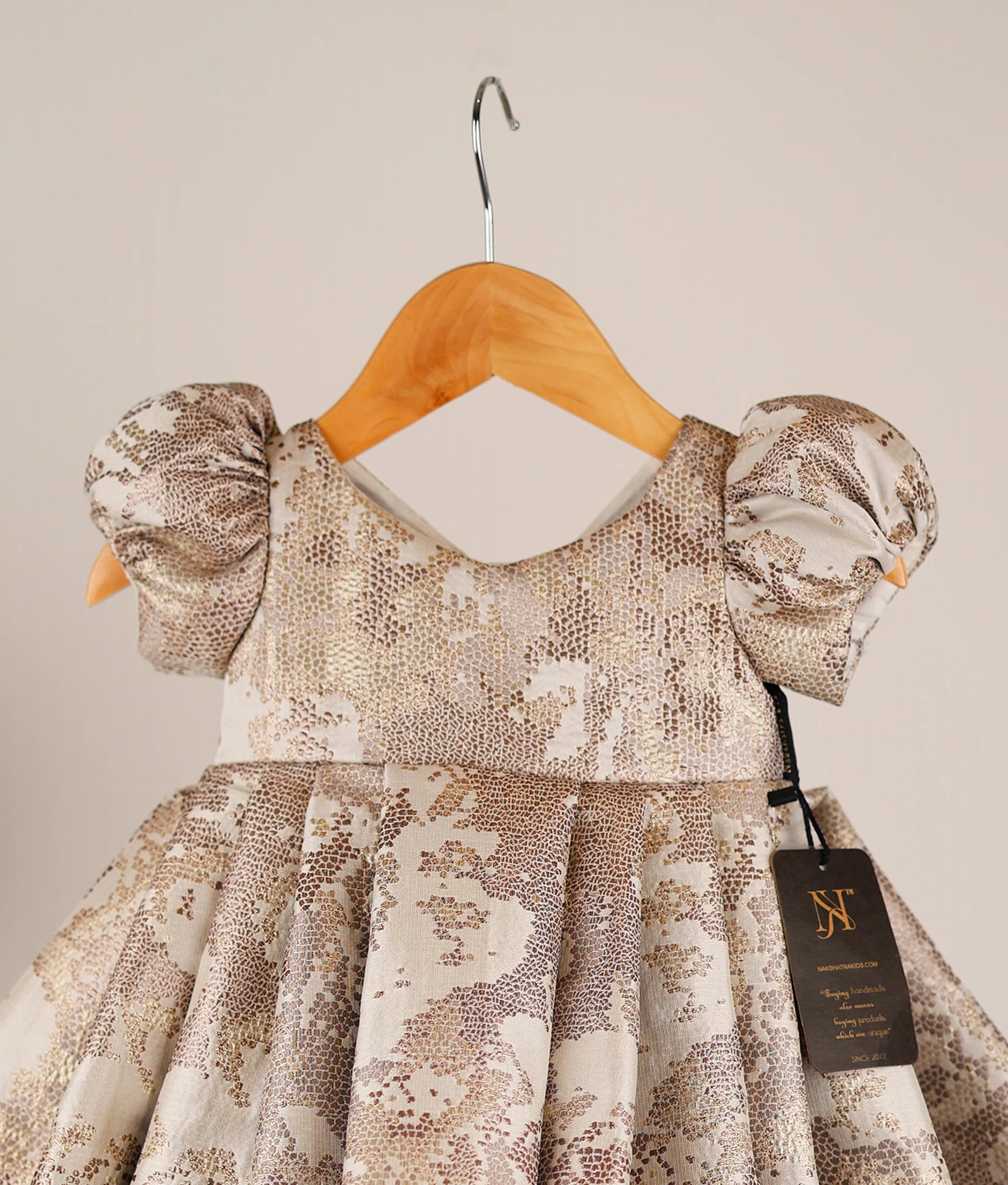 Close-up of the intricate gold jacquard organza fabric and the puff sleeve detailing.