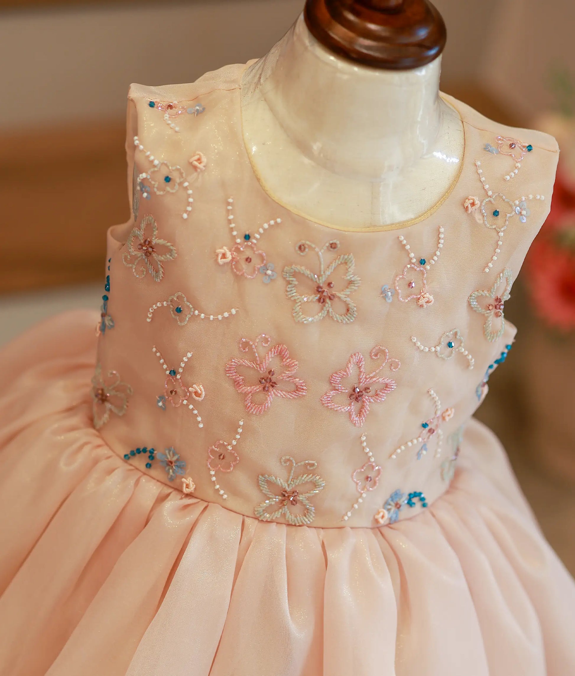 Close-up of the golden frock bodice showing the intricate pastel floral and butterfly embroidery details