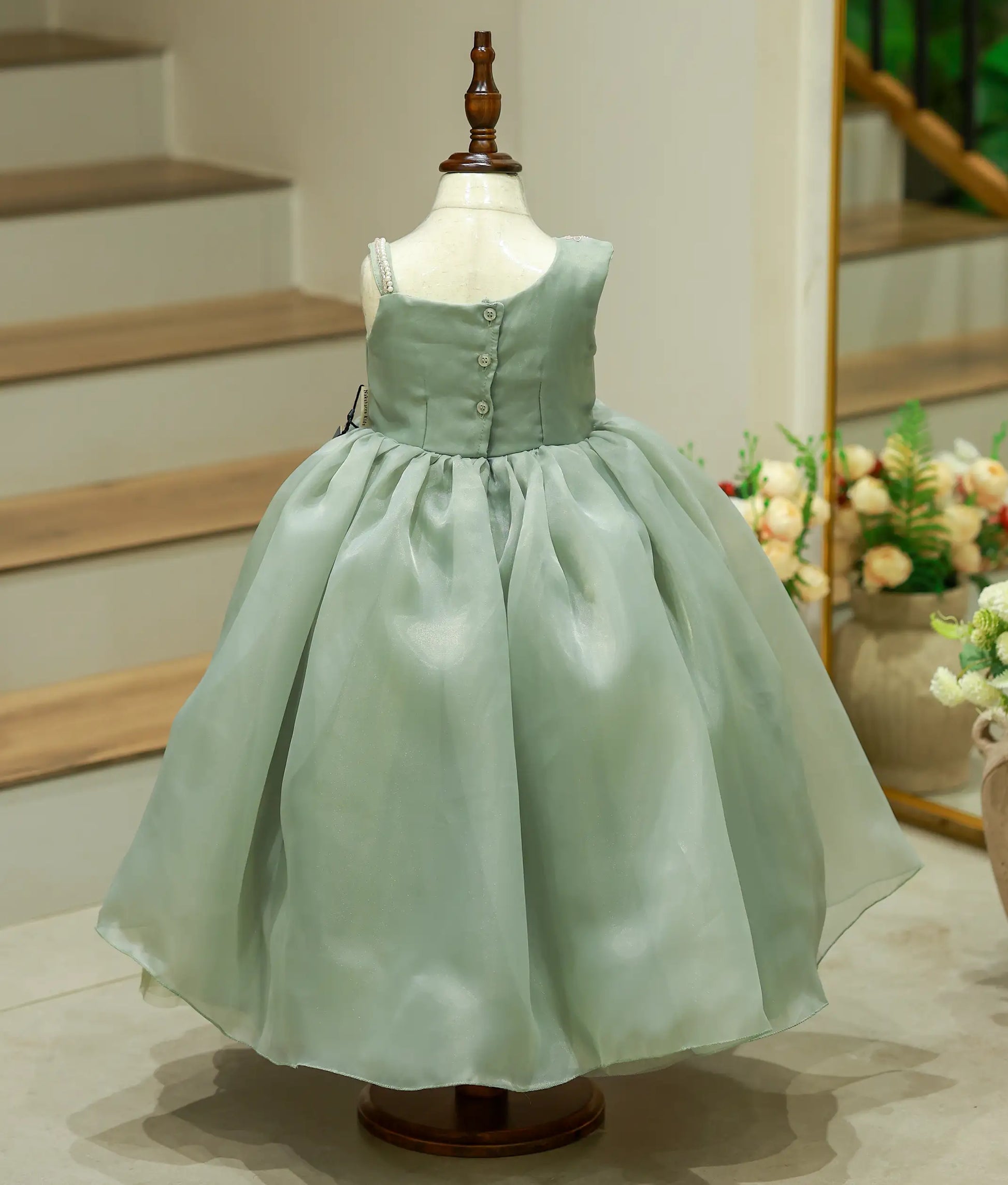 Back view of green embroidered birthday gown with full-length flared skirt