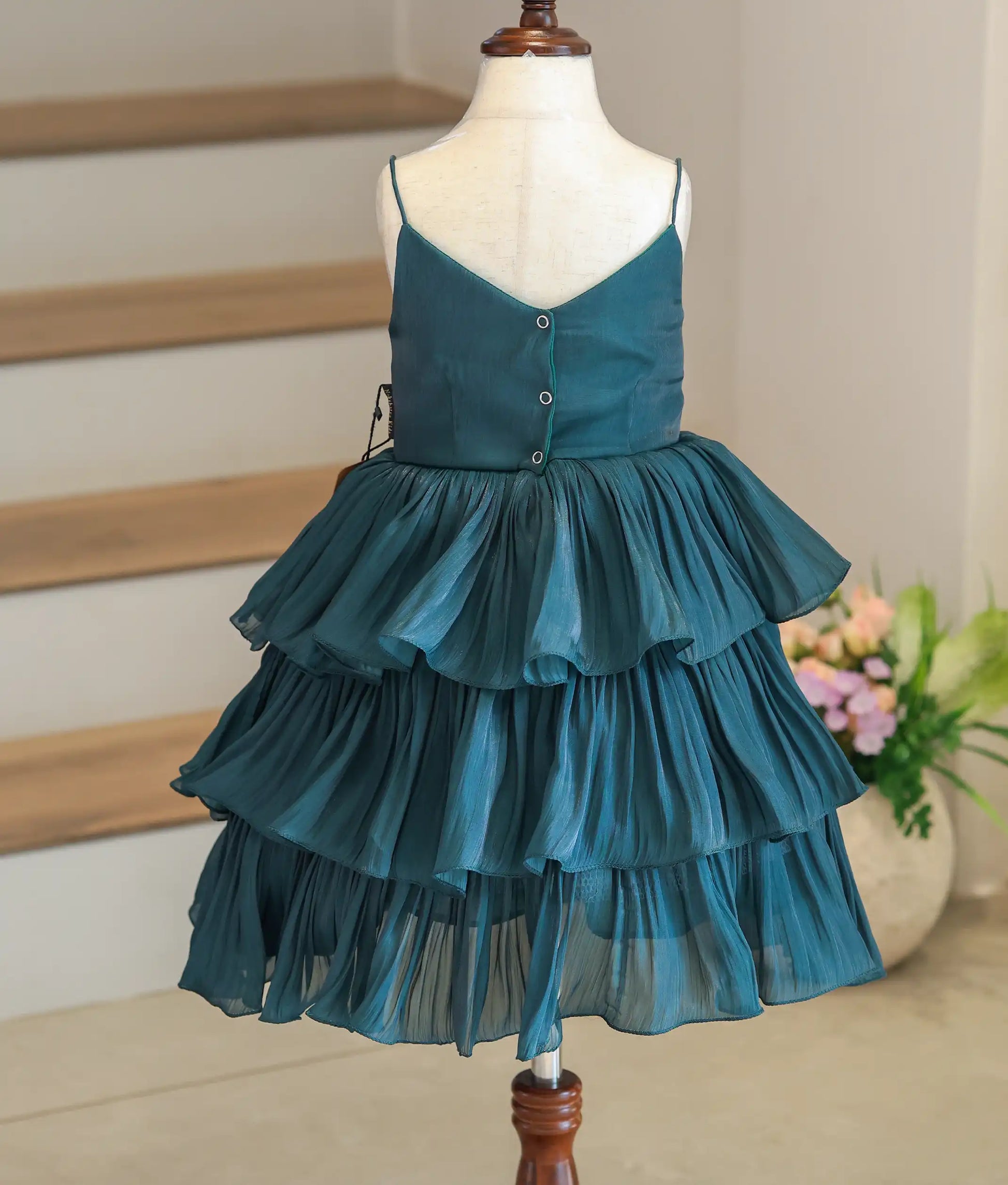 Back view of the green tiered laser organza dress showing the button closure and simple V-neck design.